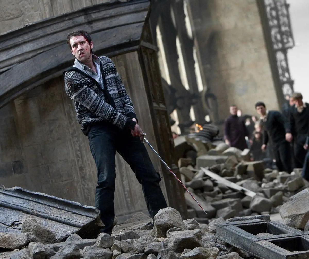 Matthew Lewis as Neville Longbottom holding the Sword of Gryffindor two-handed in the ruined Hogwarts courtyard.