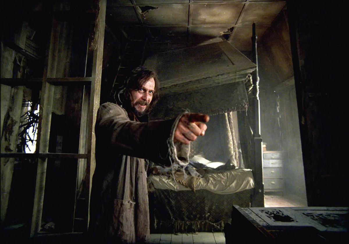 Gary Oldman as Sirius Black, ragged and wild-haired, pointing a wand across the derelict upstairs room of the Shrieking Shack.