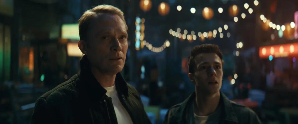 Paul Bettany as Vision and Ruaridh Mollica as Thomas Shepherd stand on a street lit by strings of lights at night in VisionQuest