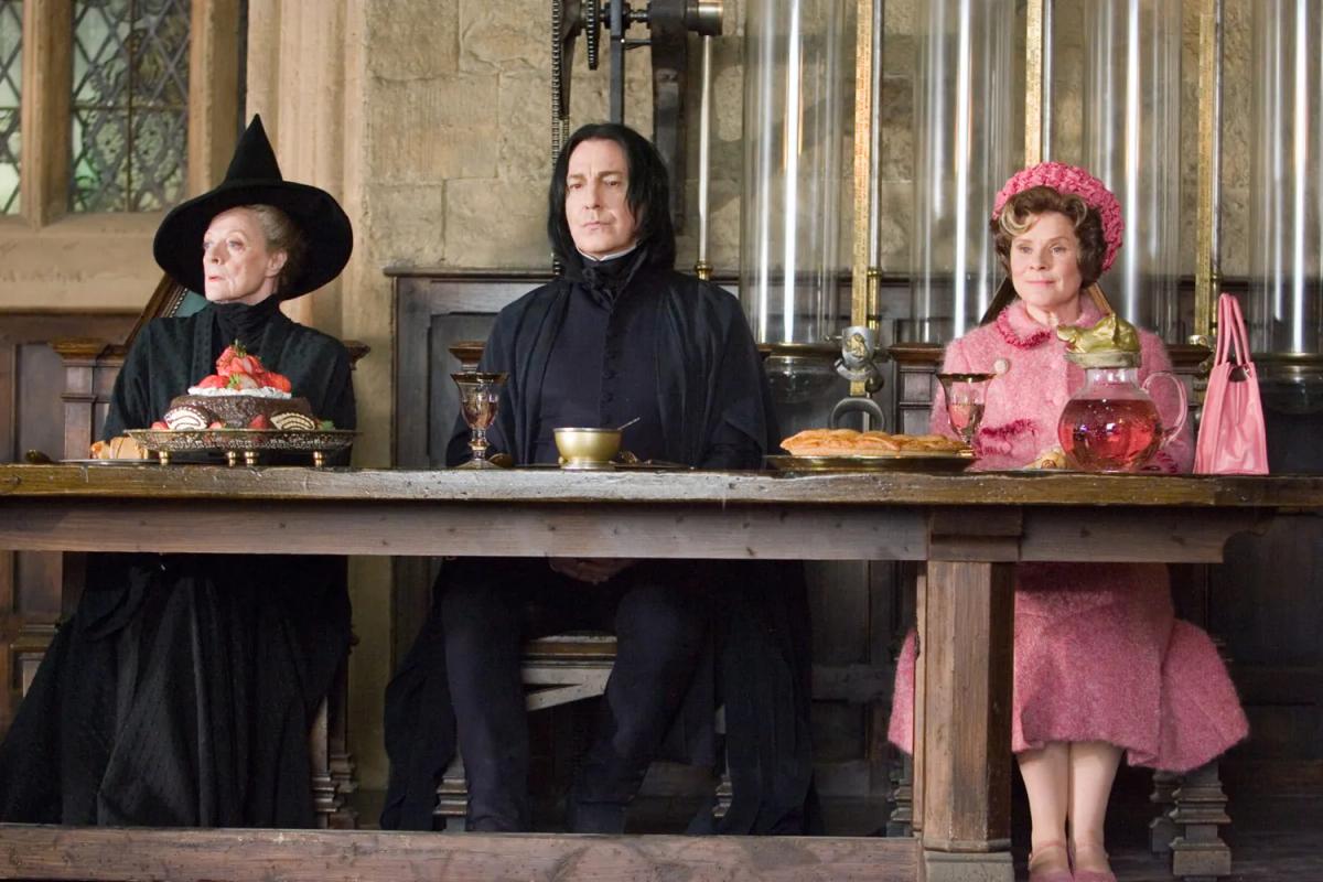 Minerva McGonagall (Maggie Smith) and Severus Snape (Alan Rickman) sit at the Hogwarts staff table beside Dolores Umbridge (Imelda Staunton), who is dressed in pink.