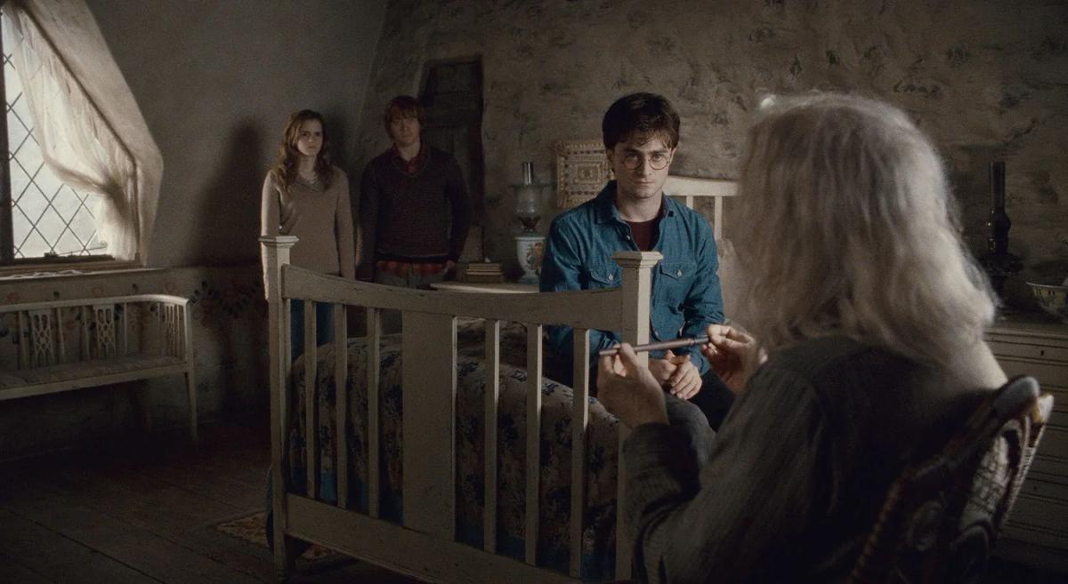 John Hurt as Garrick Ollivander holds a wand opposite Daniel Radcliffe as Harry Potter, with Emma Watson as Hermione Granger and Rupert Grint as Ron Weasley behind Harry.