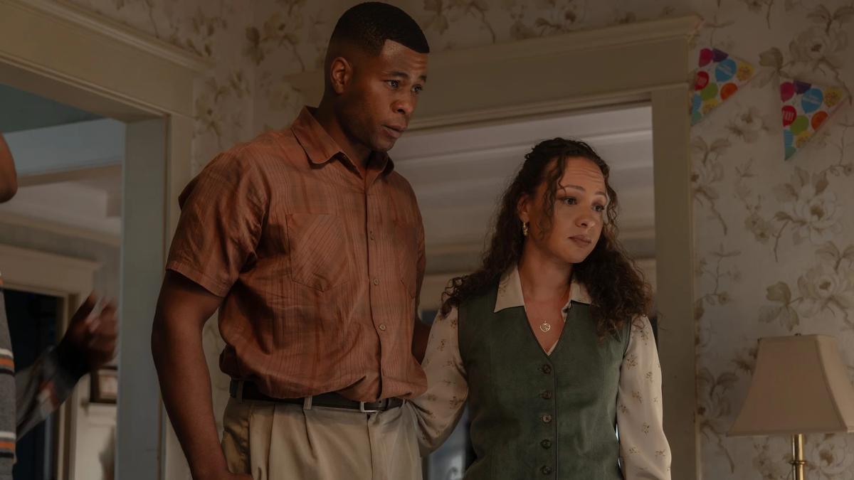 J. Alphonse Nicholson as John Stewart Sr. and Jasmine Cephas Jones as Bernadette standing together in a doorway, birthday bunting on the wall behind them.