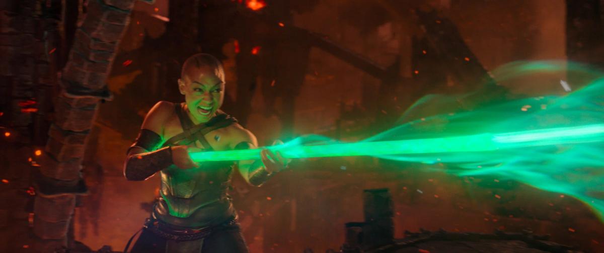 Tati Gabrielle as Jade swinging her staff, which trails a stream of green energy.