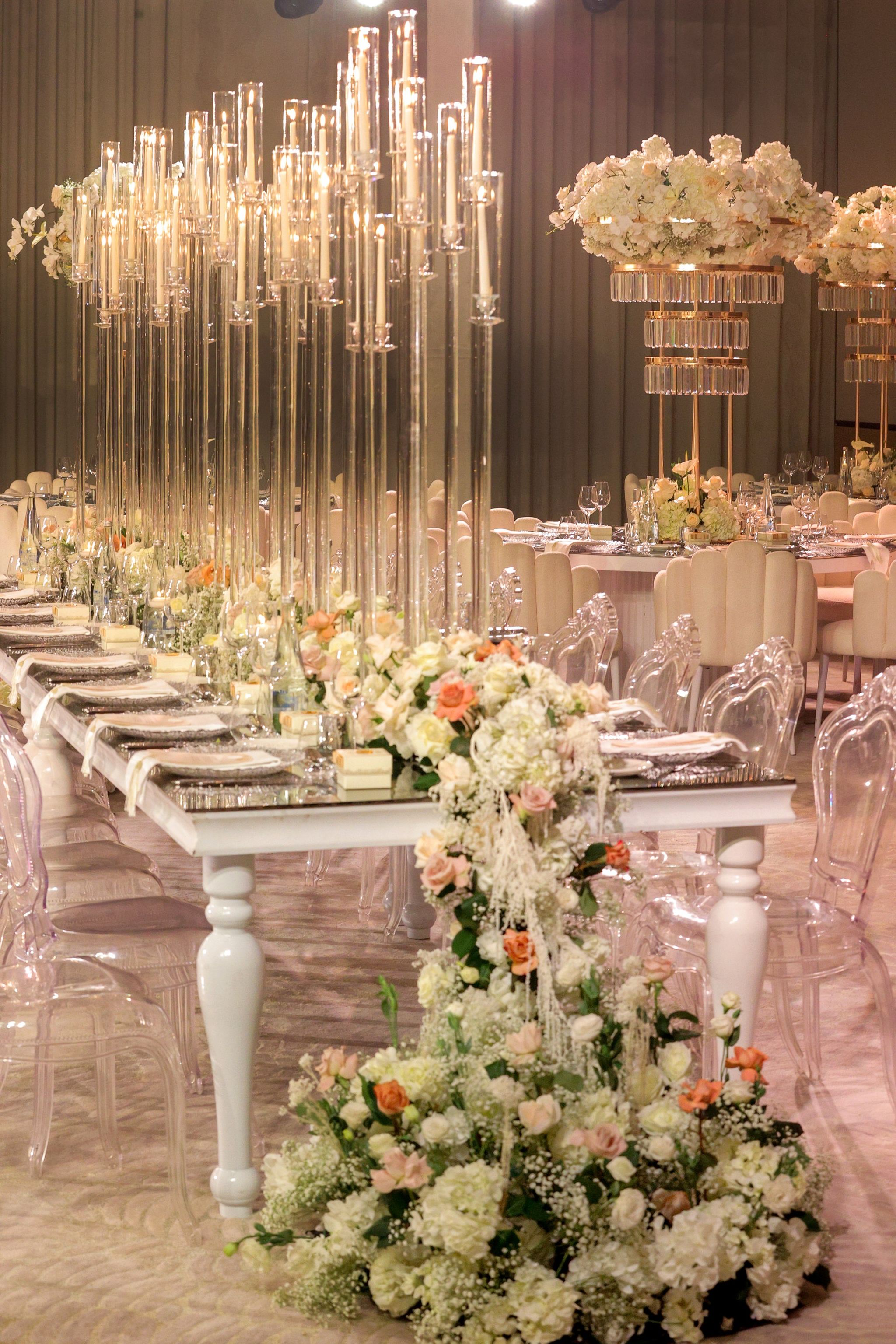 Cascade of white hydrangea and peach roses at the end of a candelabra-lined head table