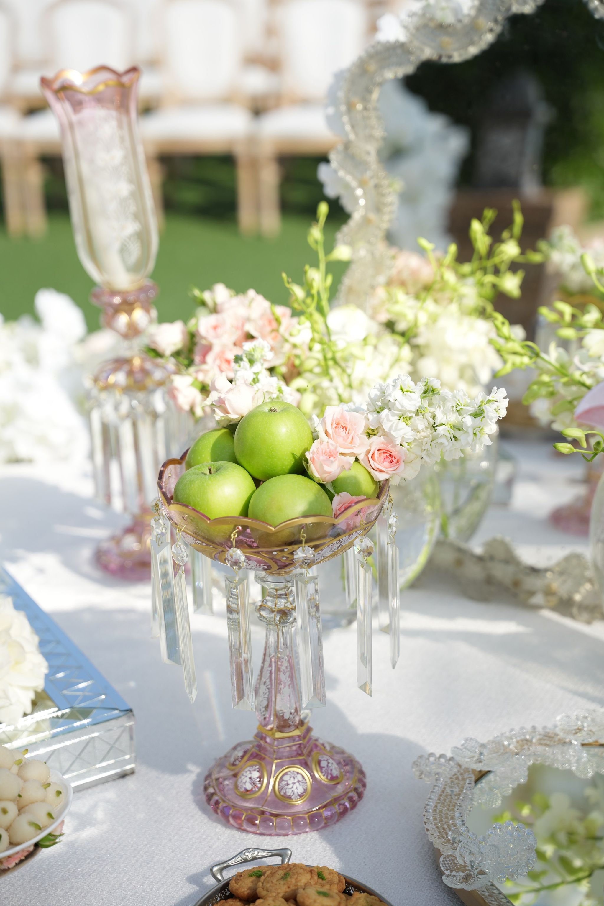 Green apples in a pink crystal compote hung with glass drops, surrounded by blush spray roses