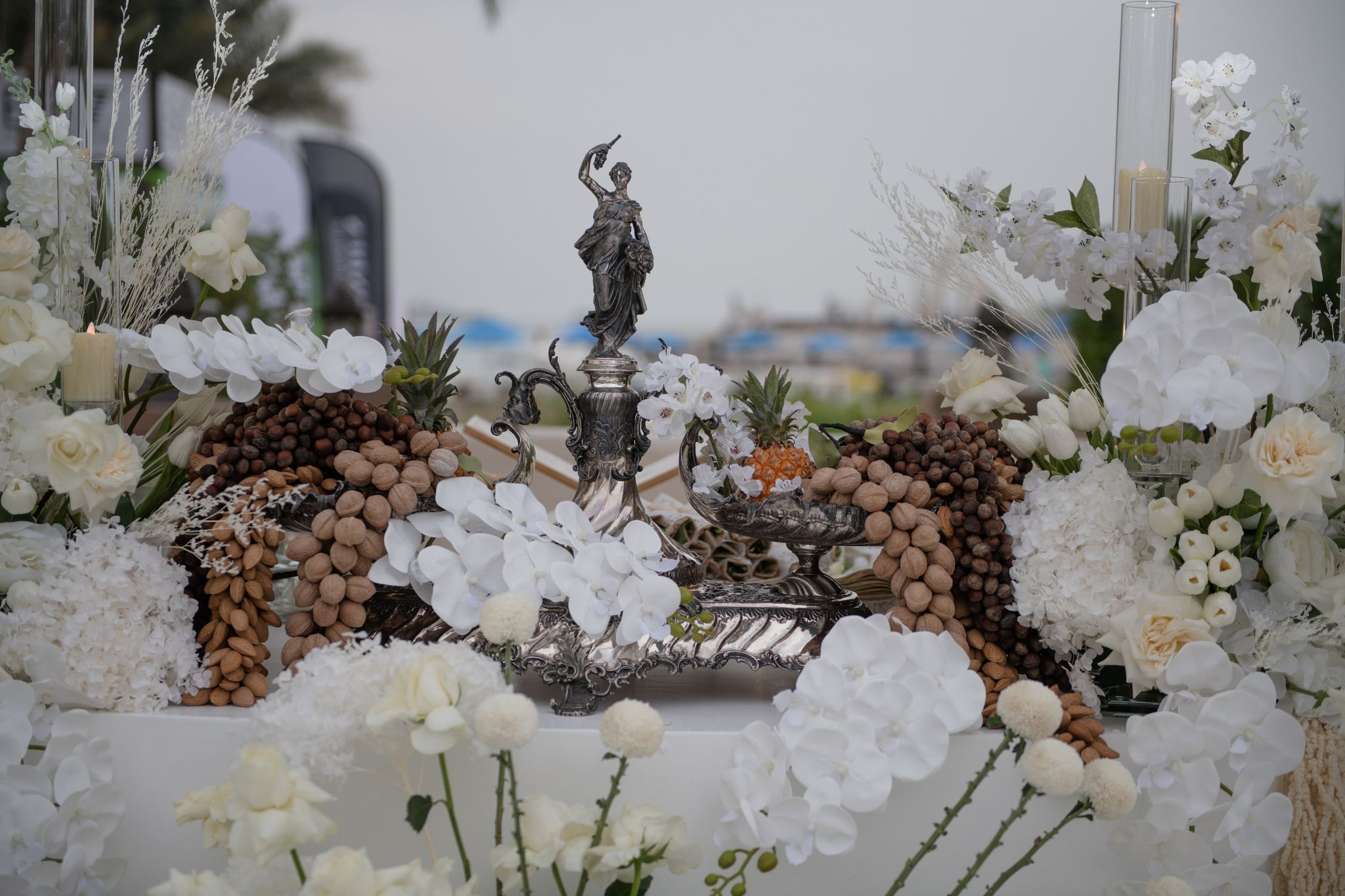 Antique silver figurine centrepiece with almond sculptures, white orchids and pineapples on the sofreh
