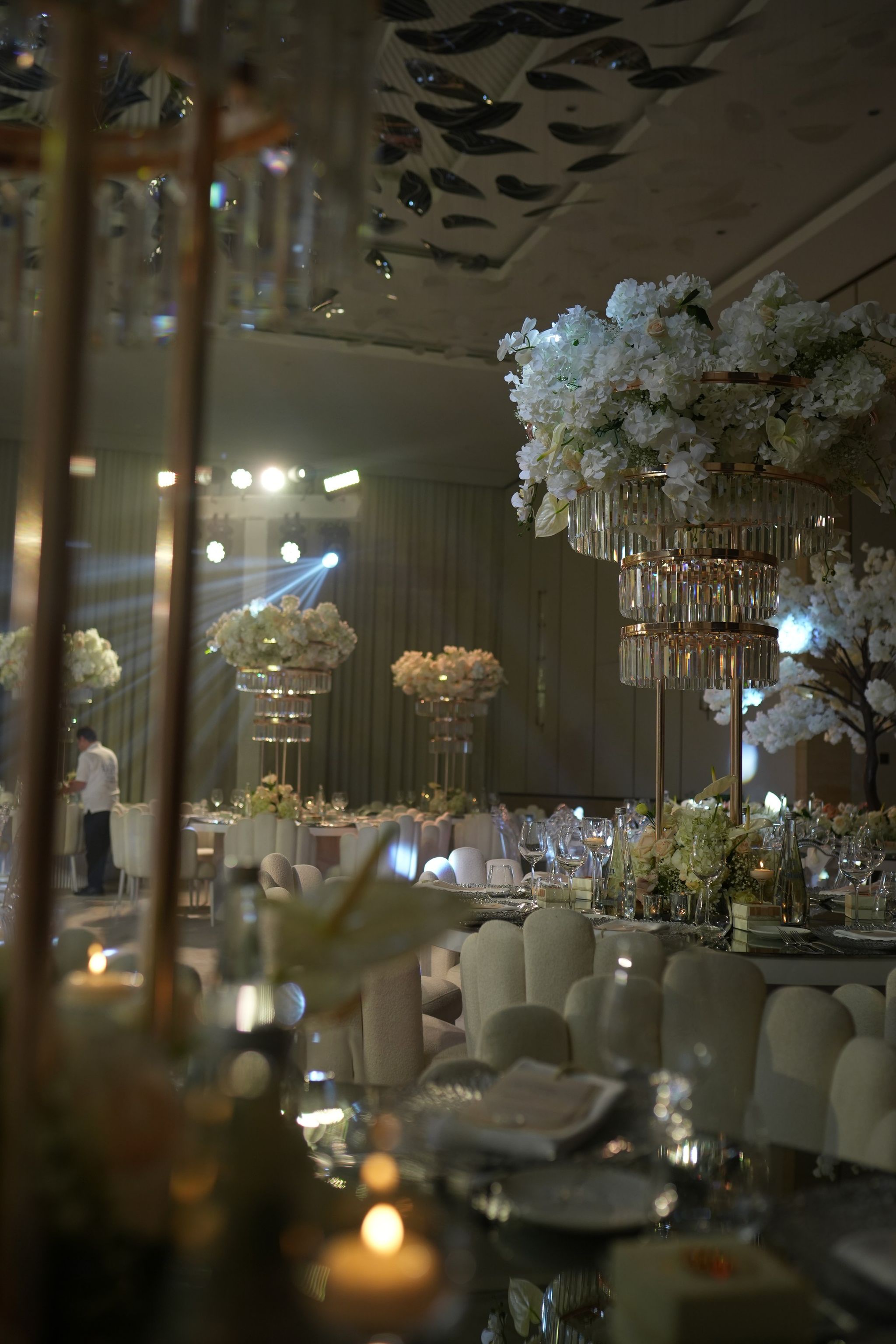 Candlelit tables under raised white floral centrepieces and stage lighting during the evening at The St. Regis Dubai, The Palm