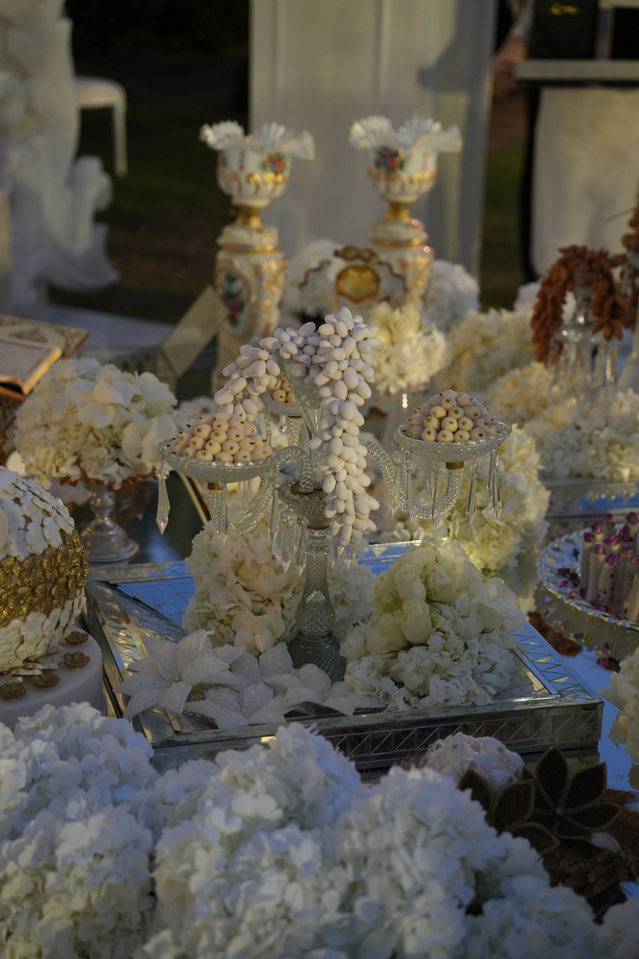Persian sofreh aghd spread with sugared almonds in crystal dishes, painted vases and white hydrangeas