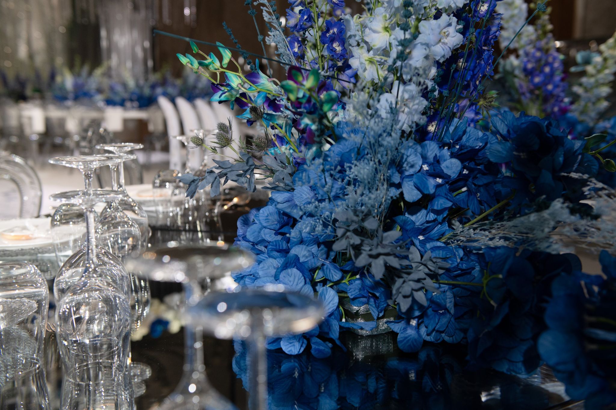 Blue hydrangeas, delphiniums and orchids beside stacked crystal glasses at Four Seasons Resort Dubai at Jumeirah Beach