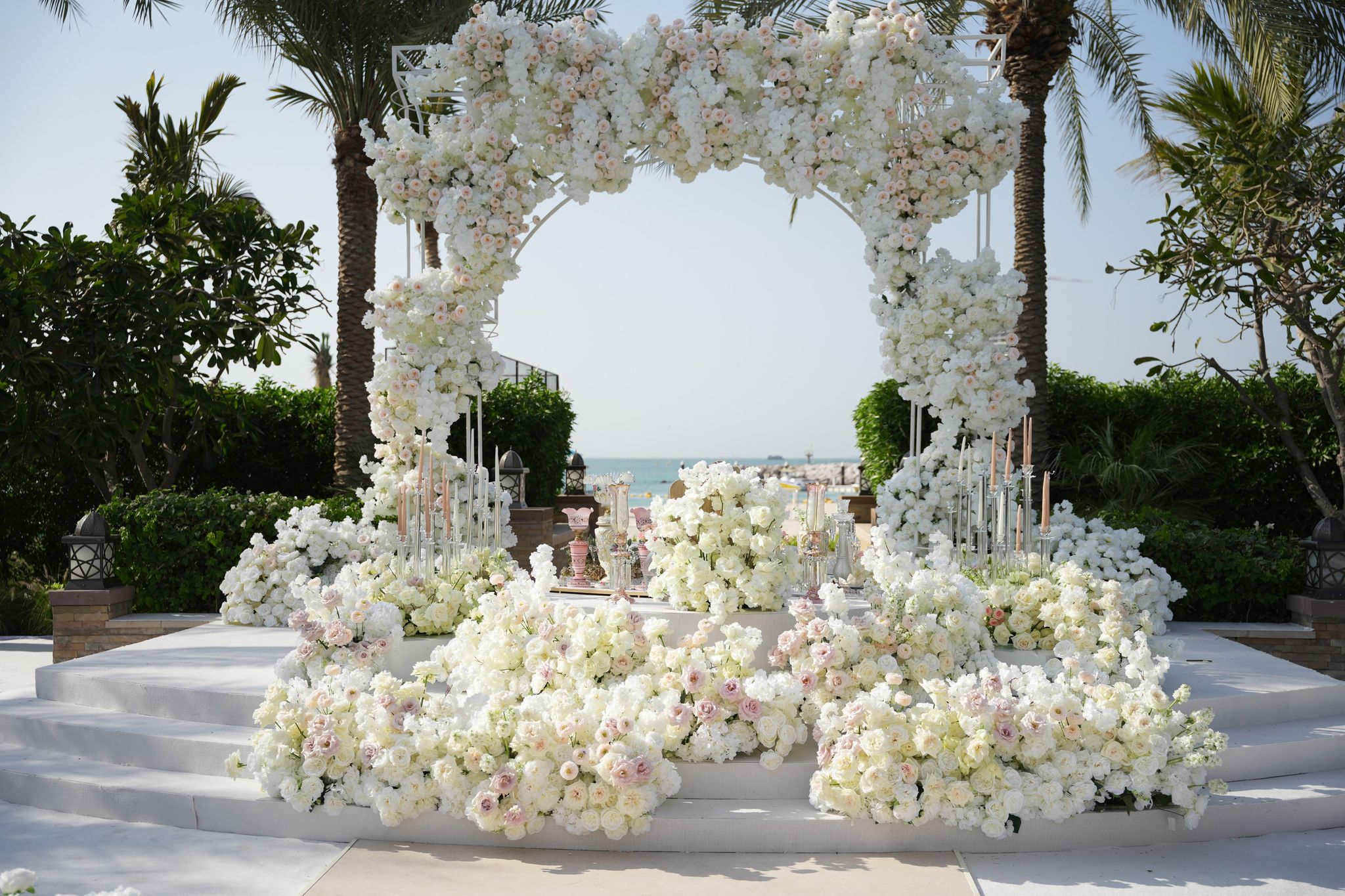 Closer view of the rose arch and stepped stage, banks of white and blush blooms at its base