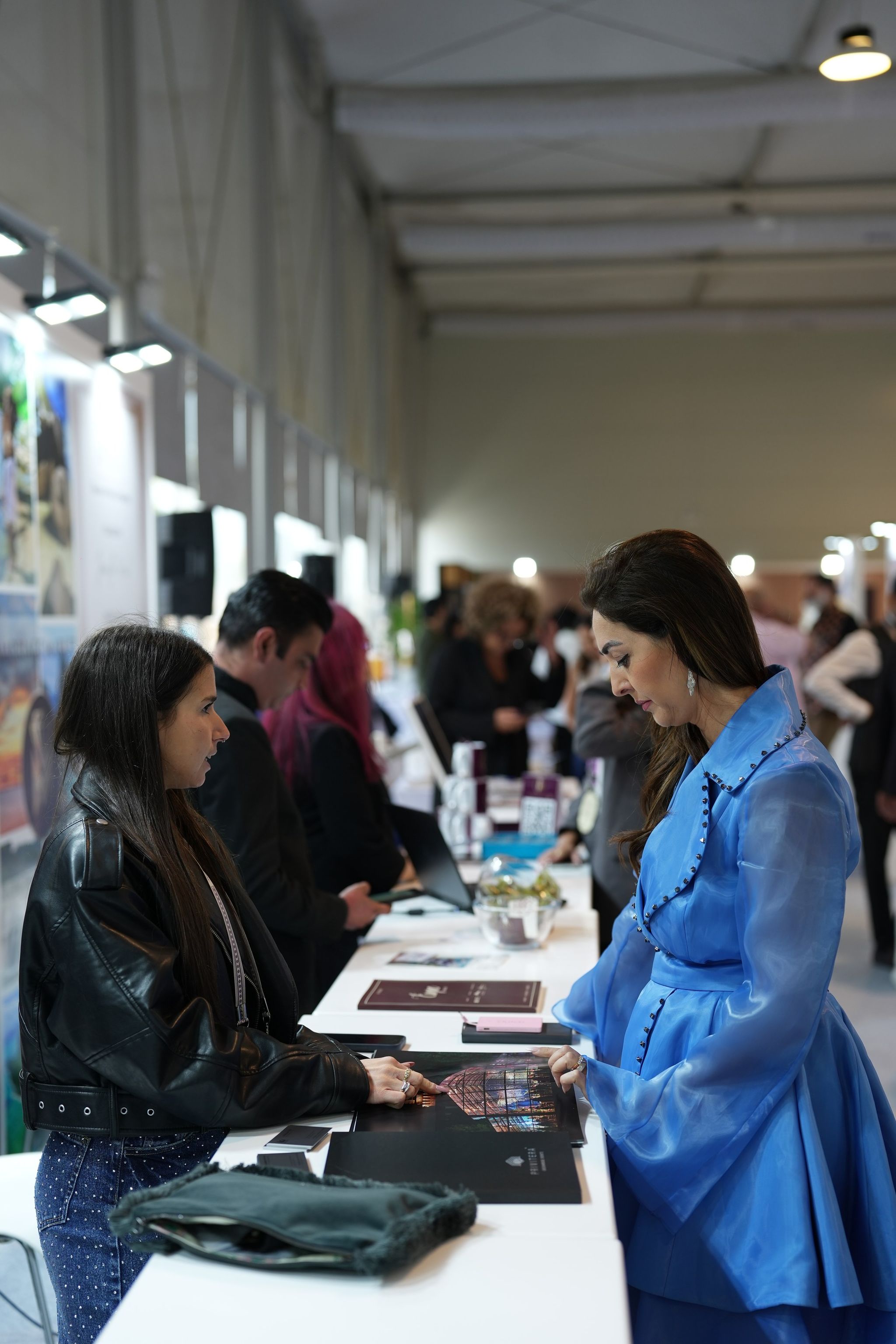 Brochures and a tablet laid out across a white counter during a meeting at a wedding exhibition