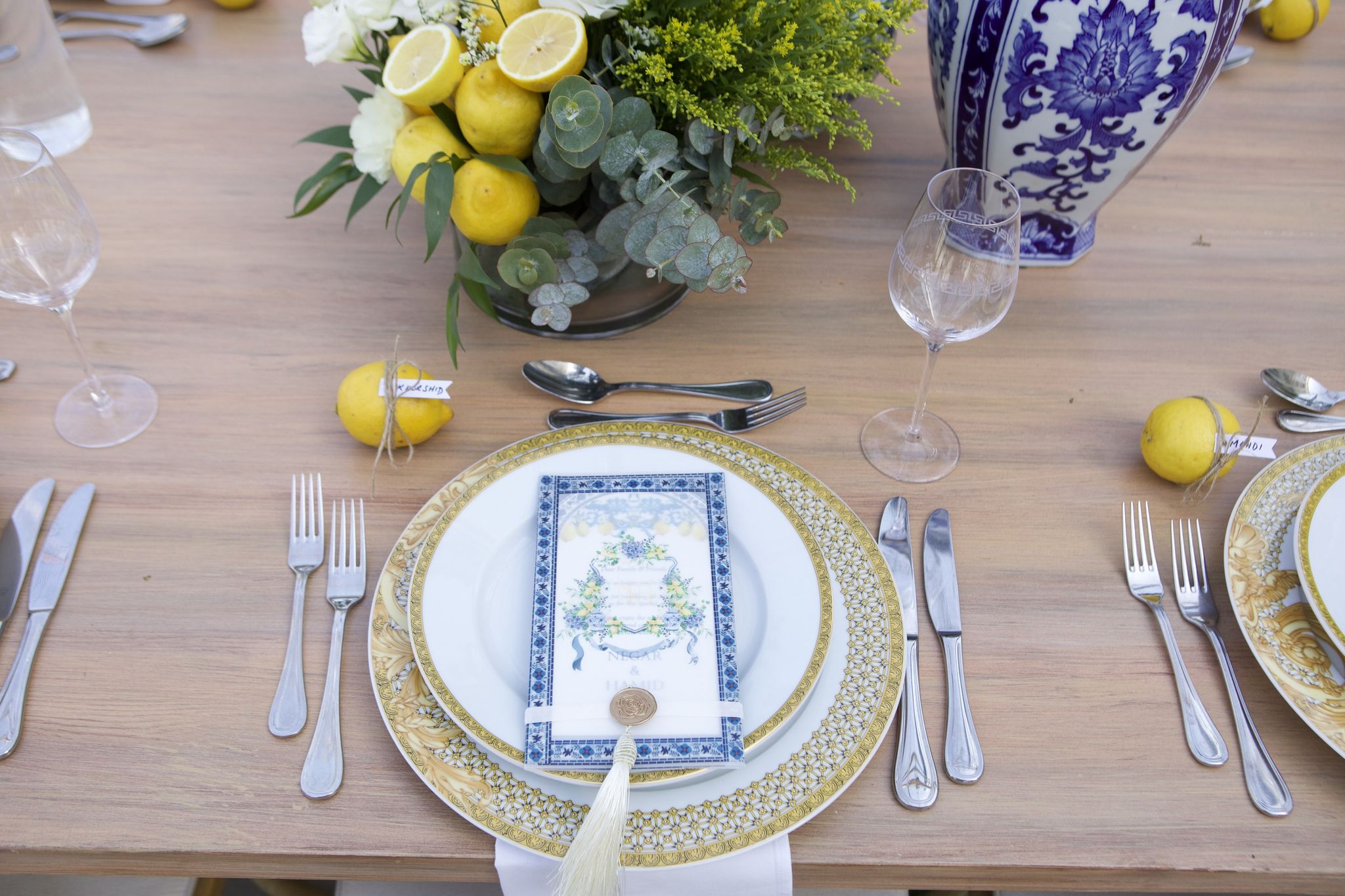 Place setting with gilded charger, blue-bordered menu, wax seal and silk tassel