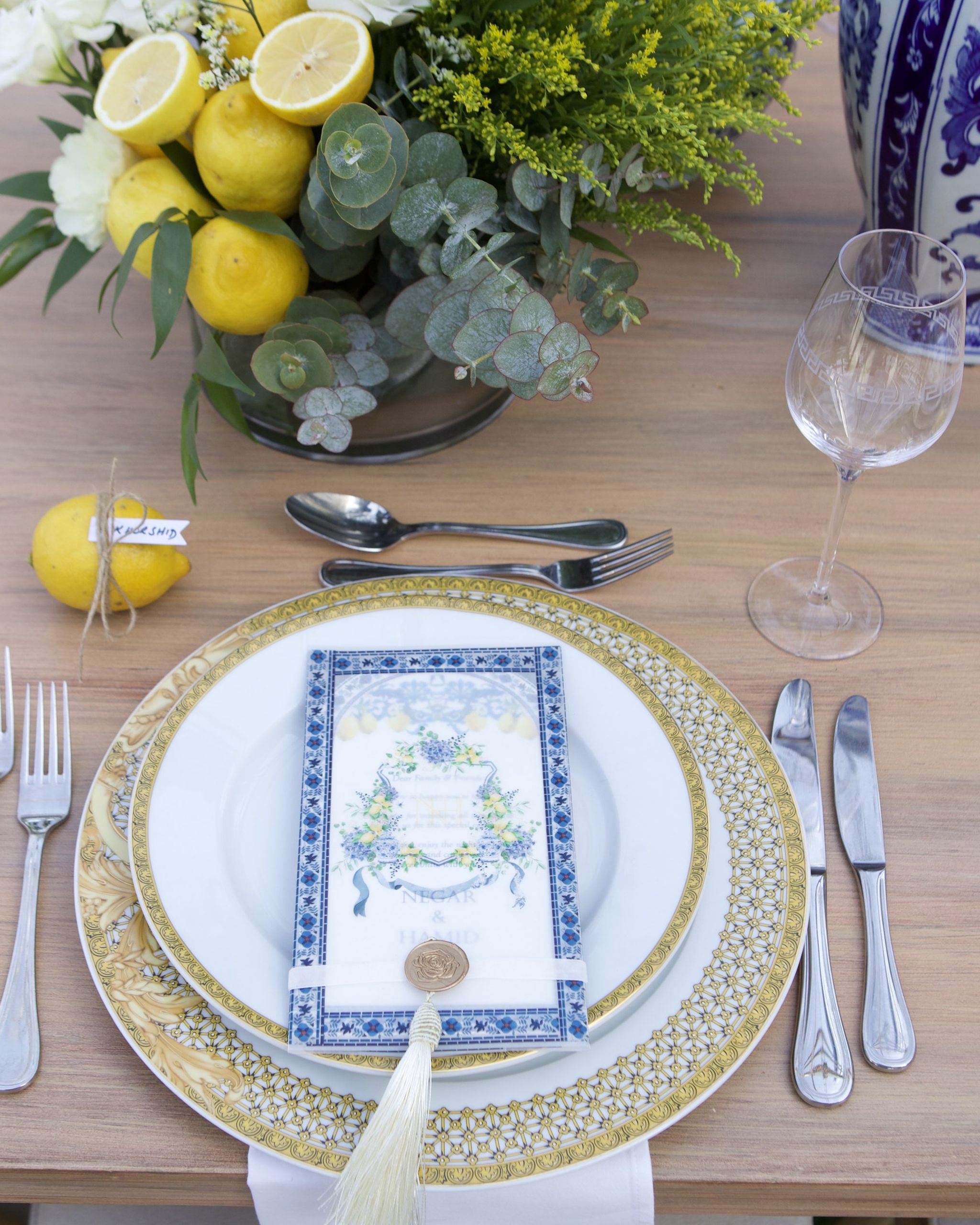Place setting with gilded charger, blue-bordered menu, wax seal and silk tassel