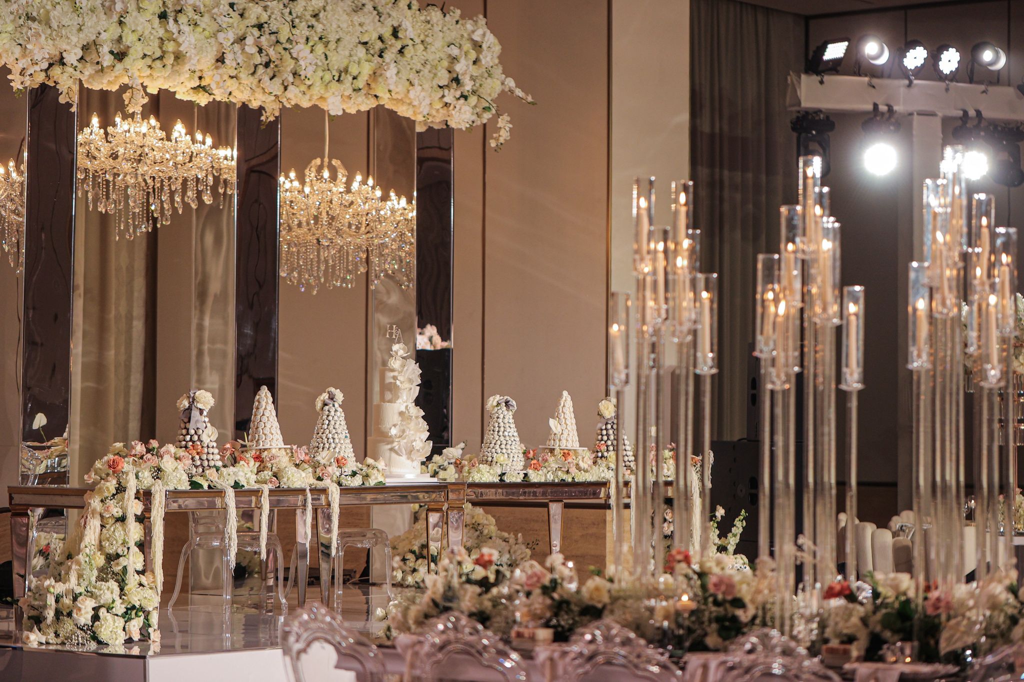 Croquembouche towers and cake on the stage beside clusters of tall glass candelabra at The St. Regis Dubai, The Palm