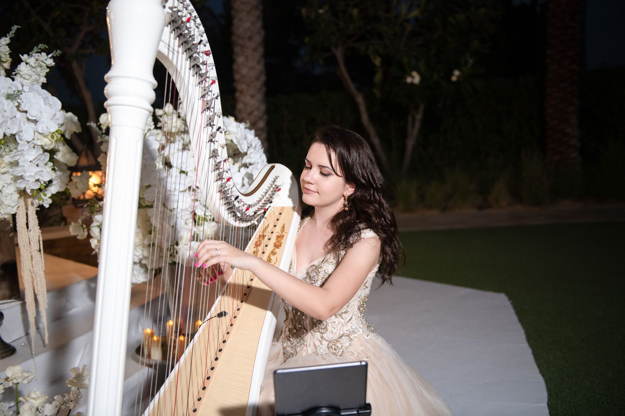 A harpist playing beside white orchids and candlelight in the garden at Four Seasons Resort Dubai at Jumeirah Beach