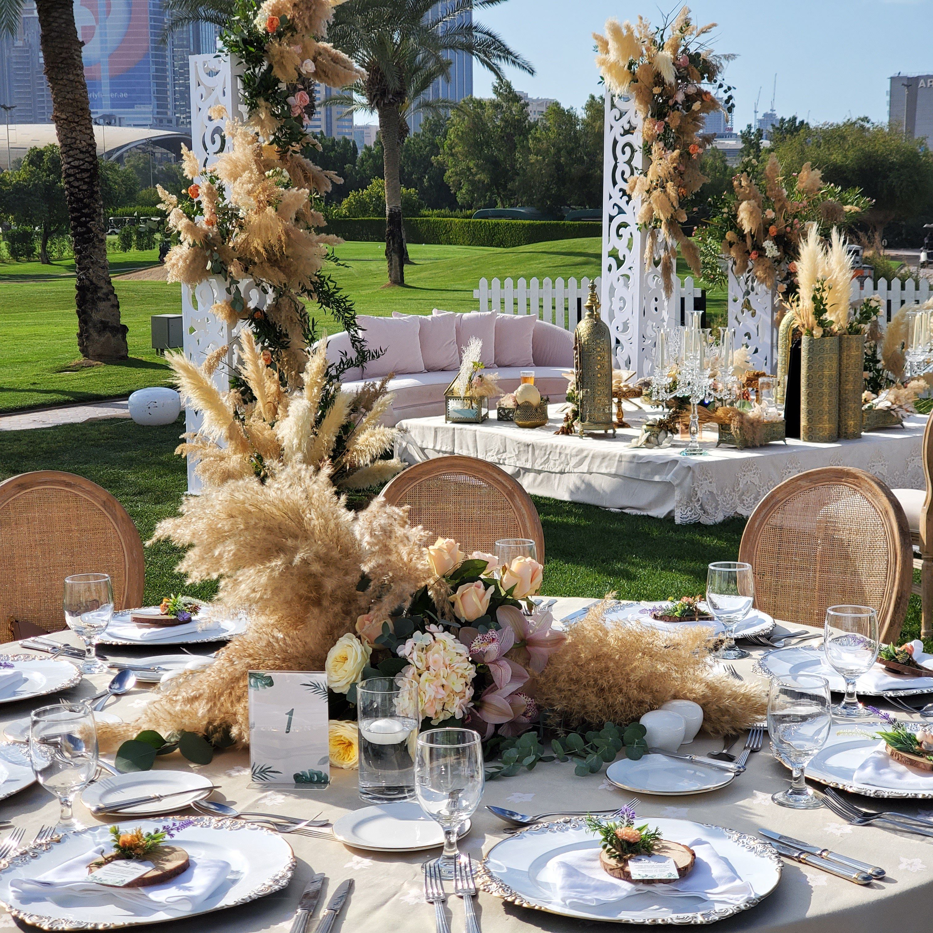 Round table with a pampas grass, rose and orchid centrepiece before the ceremony lounge