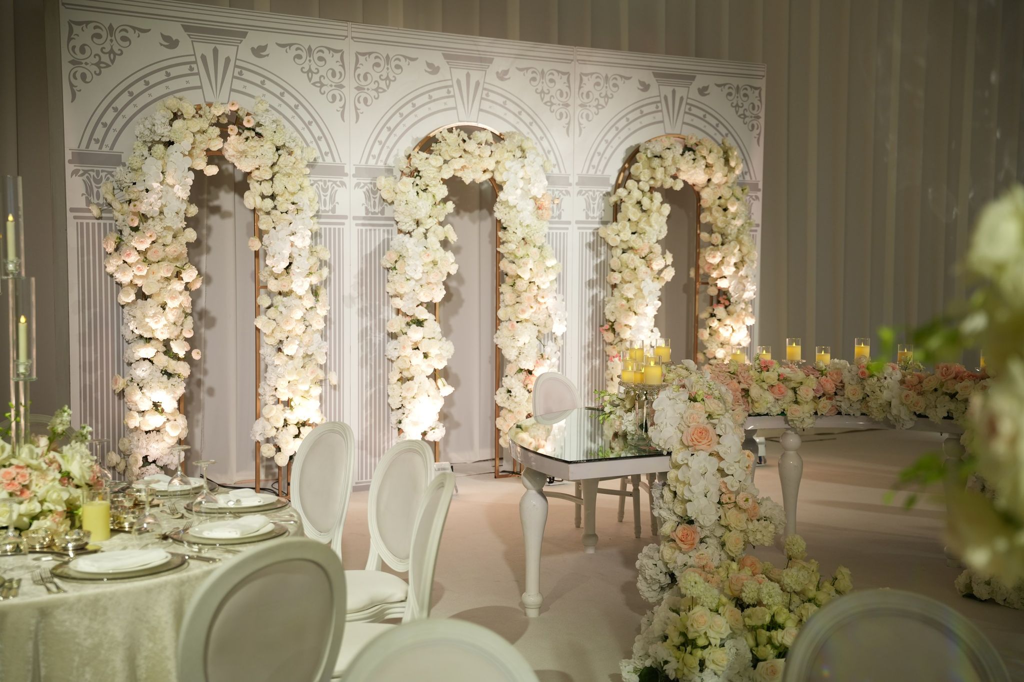Side view of the floral-arched head table with a laid guest table in the foreground