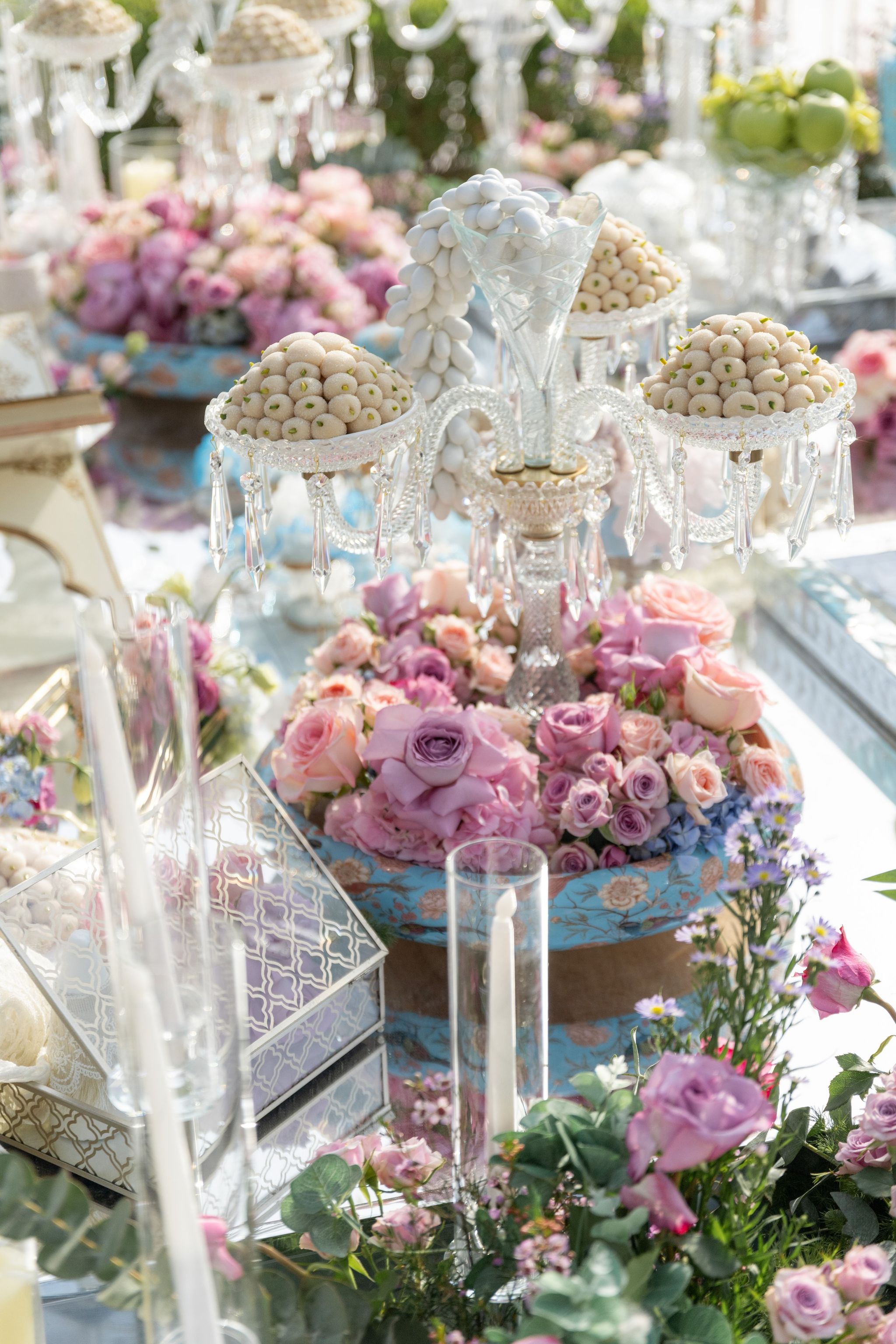 Crystal candelabrum of sugared almonds over a turquoise painted bowl of lilac and blush roses