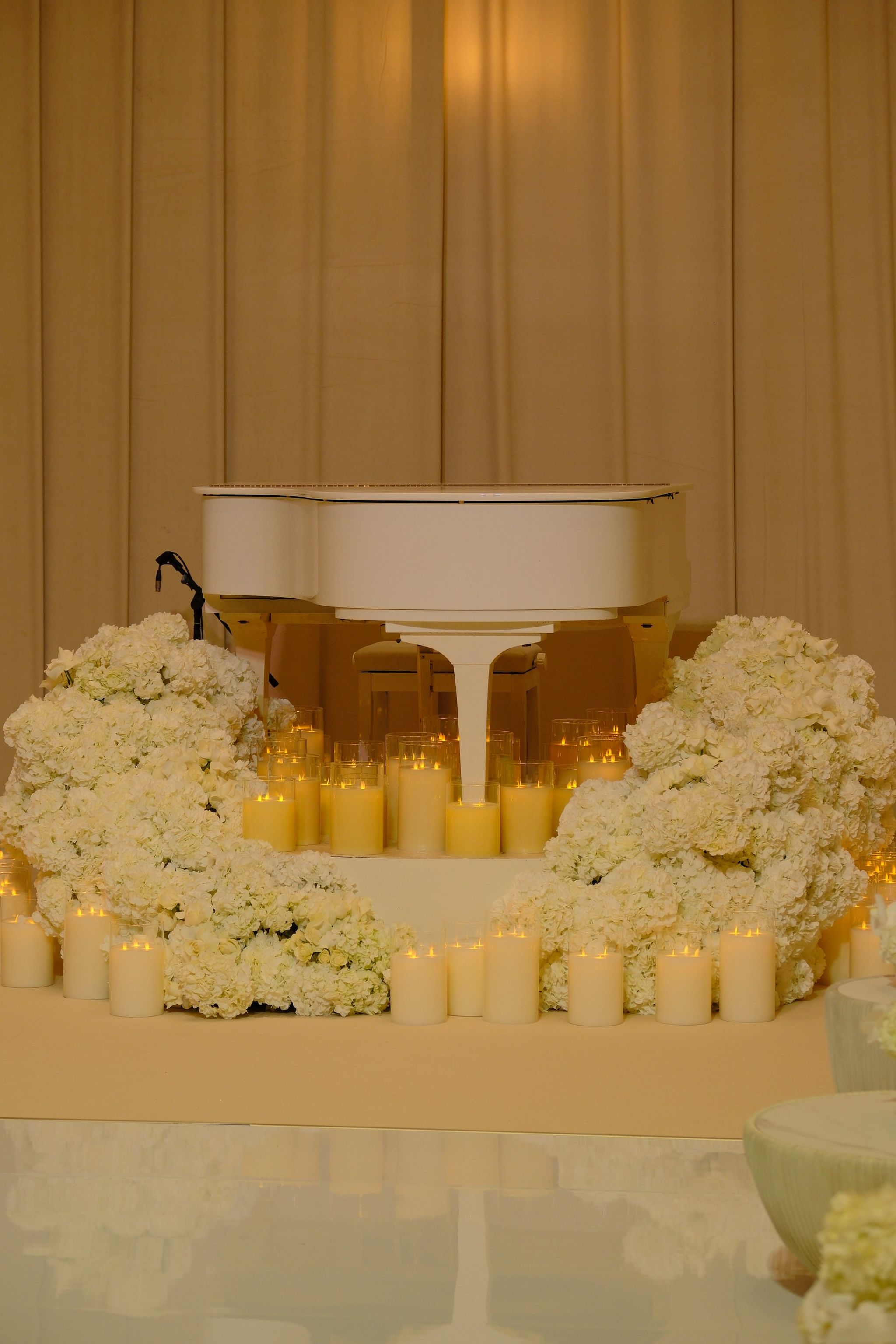 Candlelit ballroom with ivory dining chairs, hydrangea banks and the suspended floral cake installation beyond