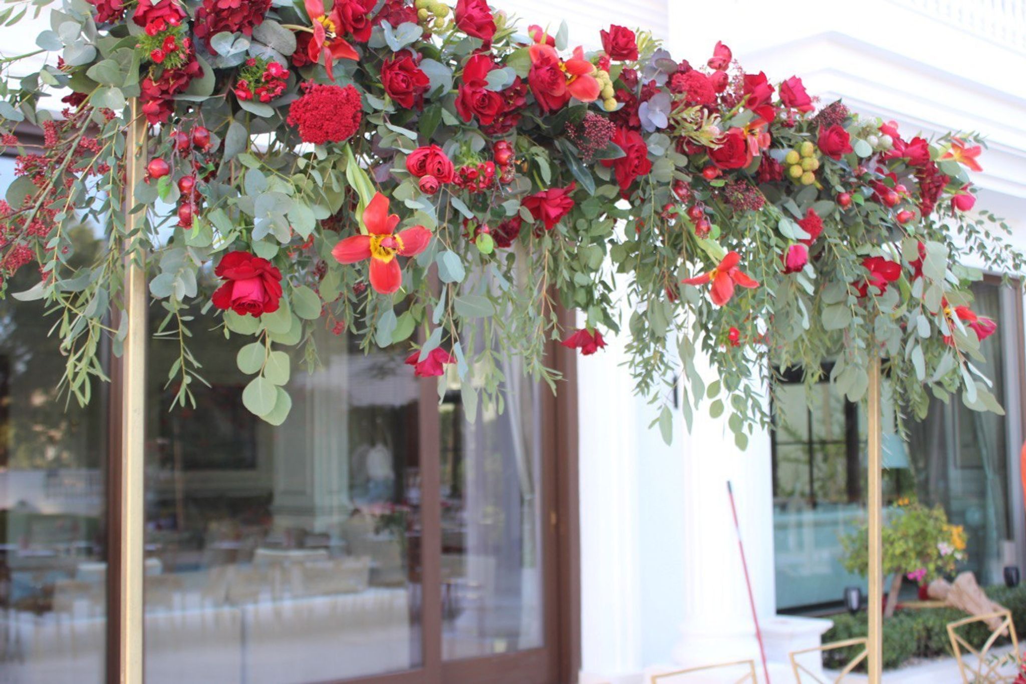 Close view of a hanging installation of red roses, lilies, berries and silver eucalyptus