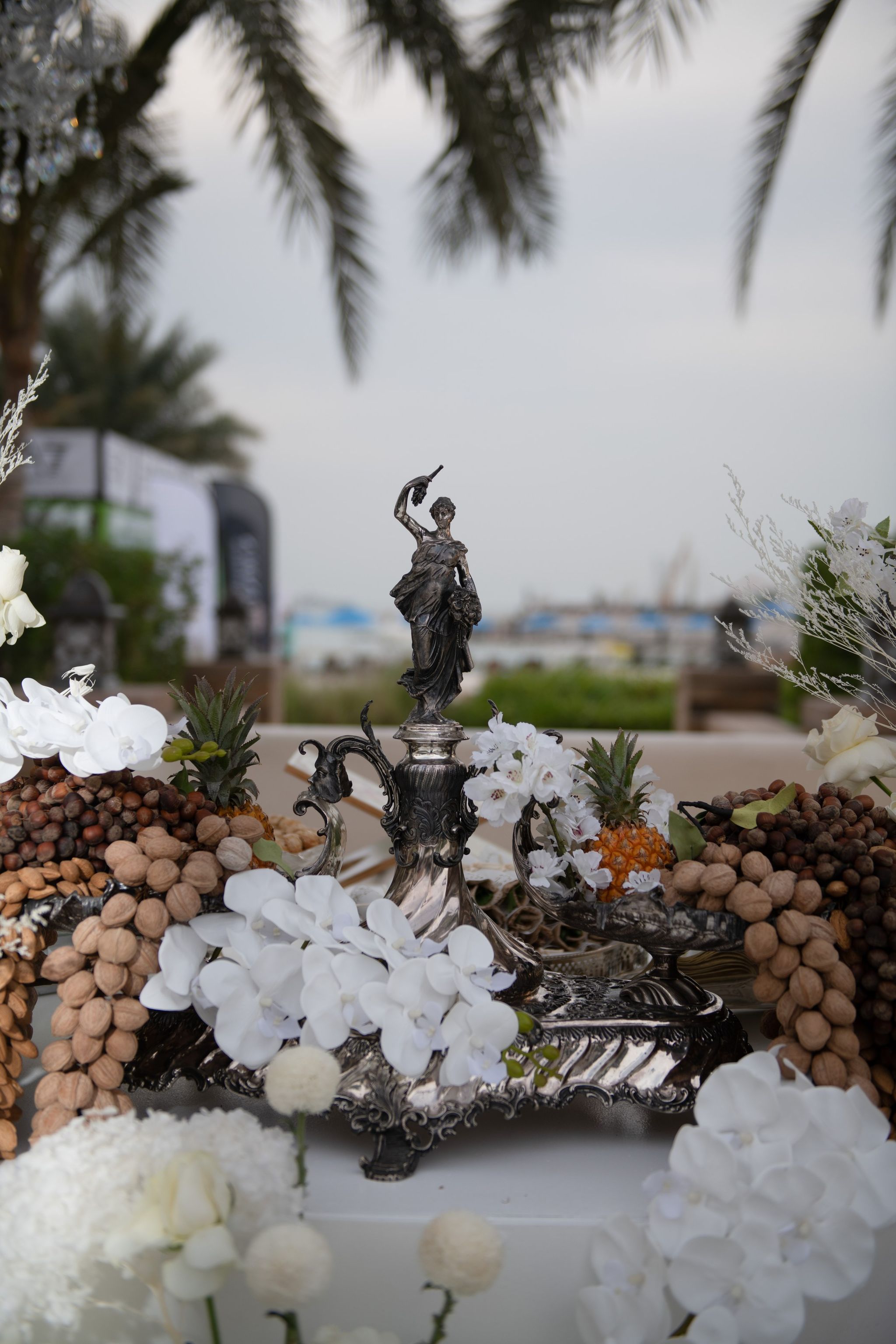 Portrait view of the silver figurine centrepiece among almonds, hazelnuts and white orchids