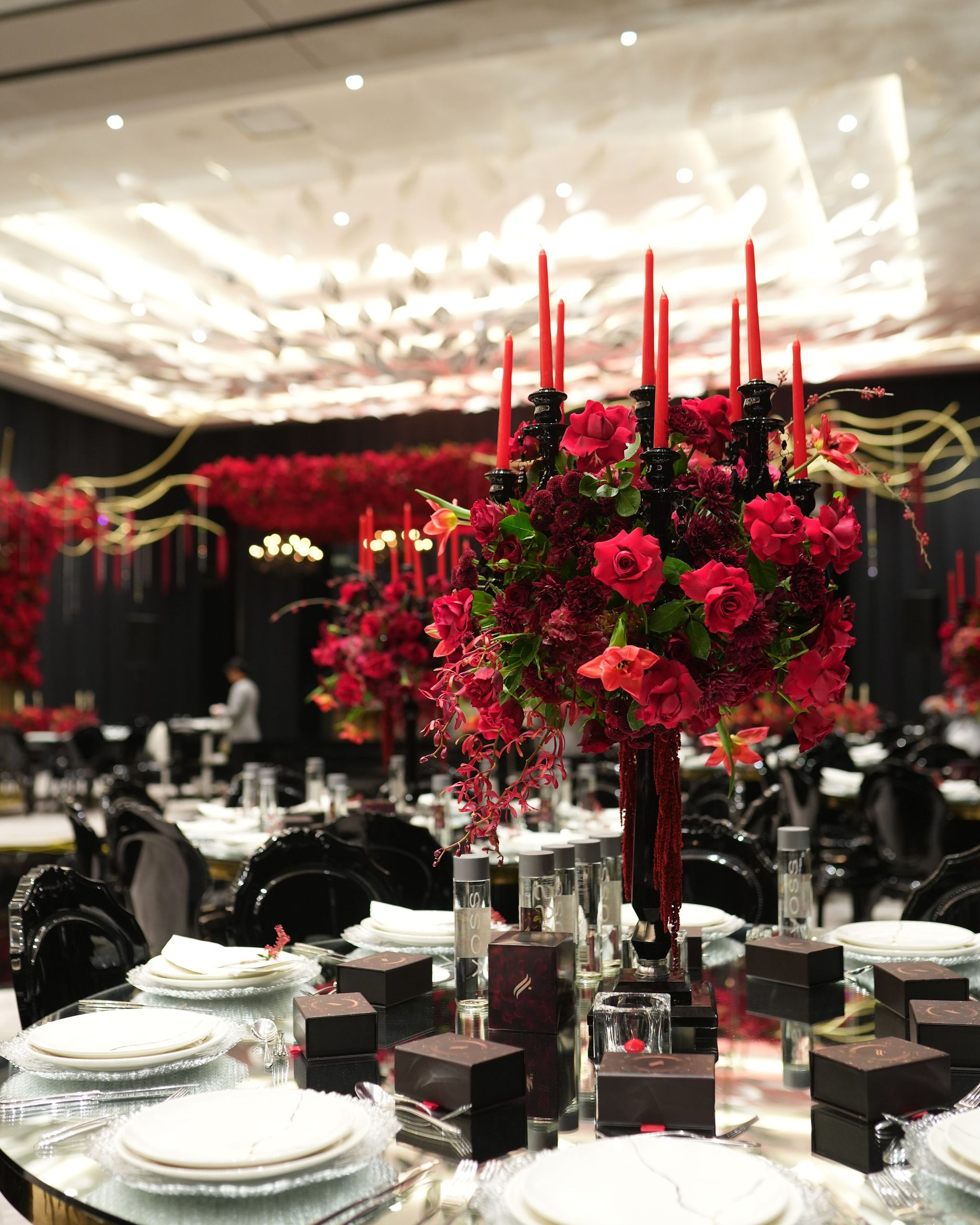 Red rose centrepiece with tall red tapers on a gold-rimmed mirrored table at The St. Regis Dubai, The Palm