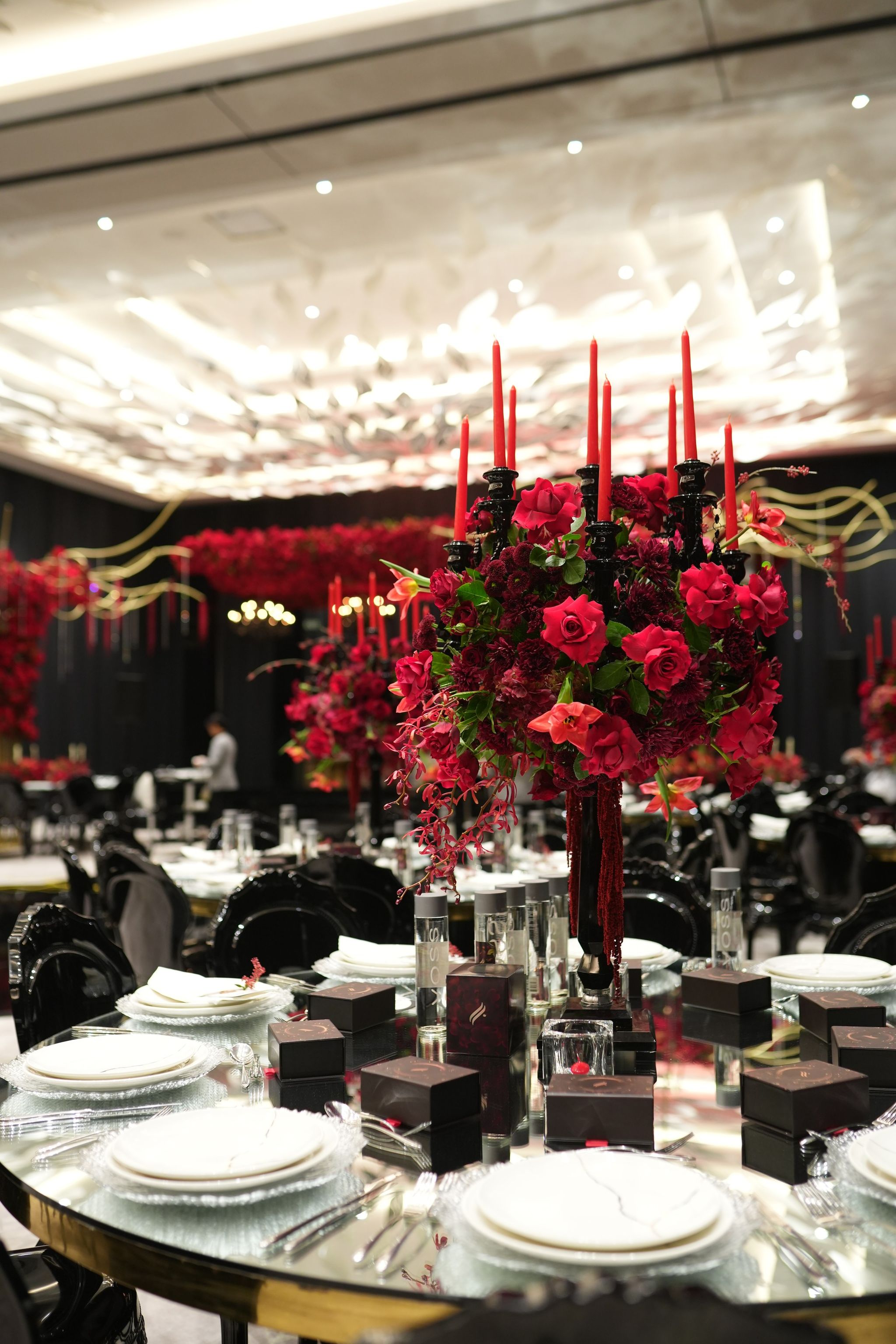 Red rose centrepiece with tall red tapers on a gold-rimmed mirrored table at The St. Regis Dubai, The Palm
