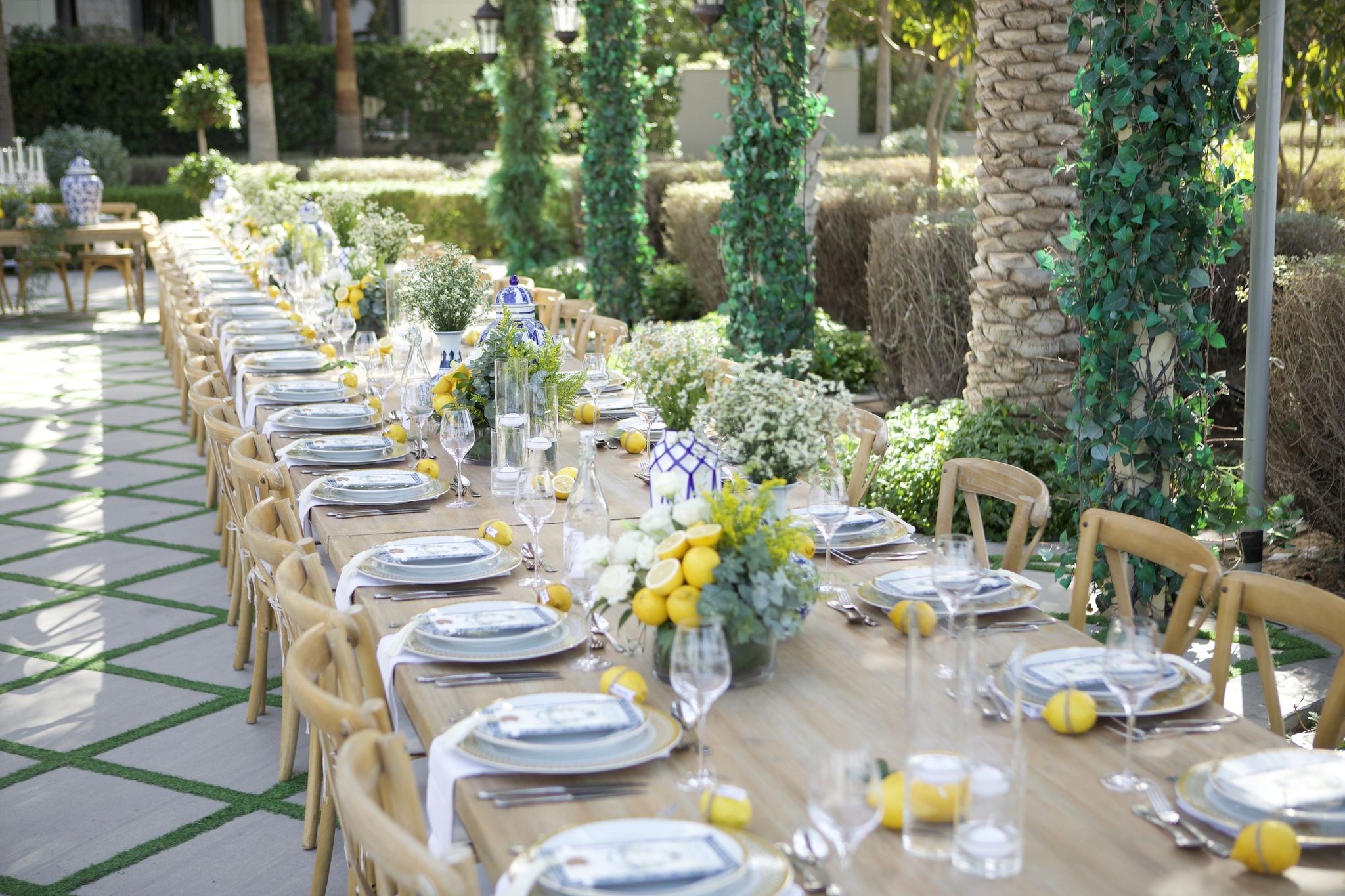 Long timber tables dressed with lemons and blue-and-white porcelain in the garden courtyard of Palazzo Versace Dubai