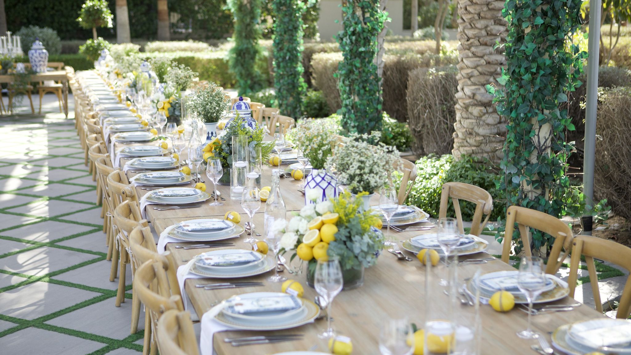 Long timber tables dressed with lemons and blue-and-white porcelain in the garden courtyard of Palazzo Versace Dubai