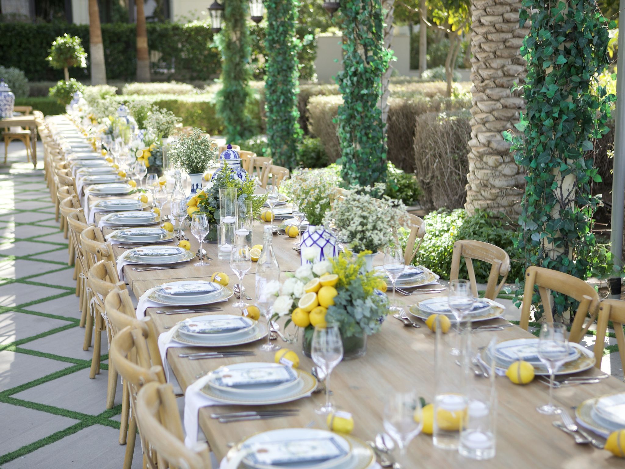 Long timber tables dressed with lemons and blue-and-white porcelain in the garden courtyard of Palazzo Versace Dubai