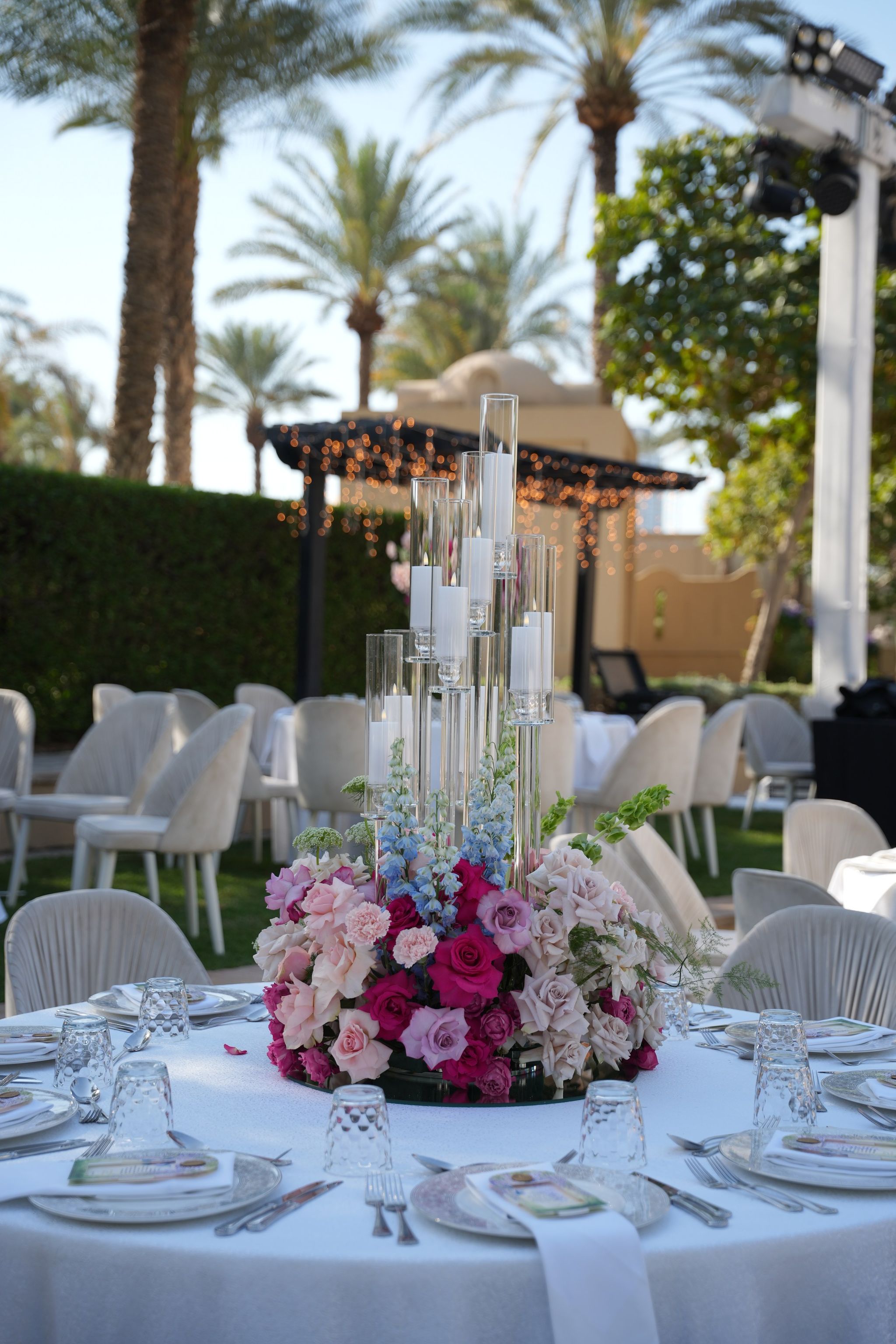 Crystal candelabra rising from a ring of fuchsia and blush roses on a white table