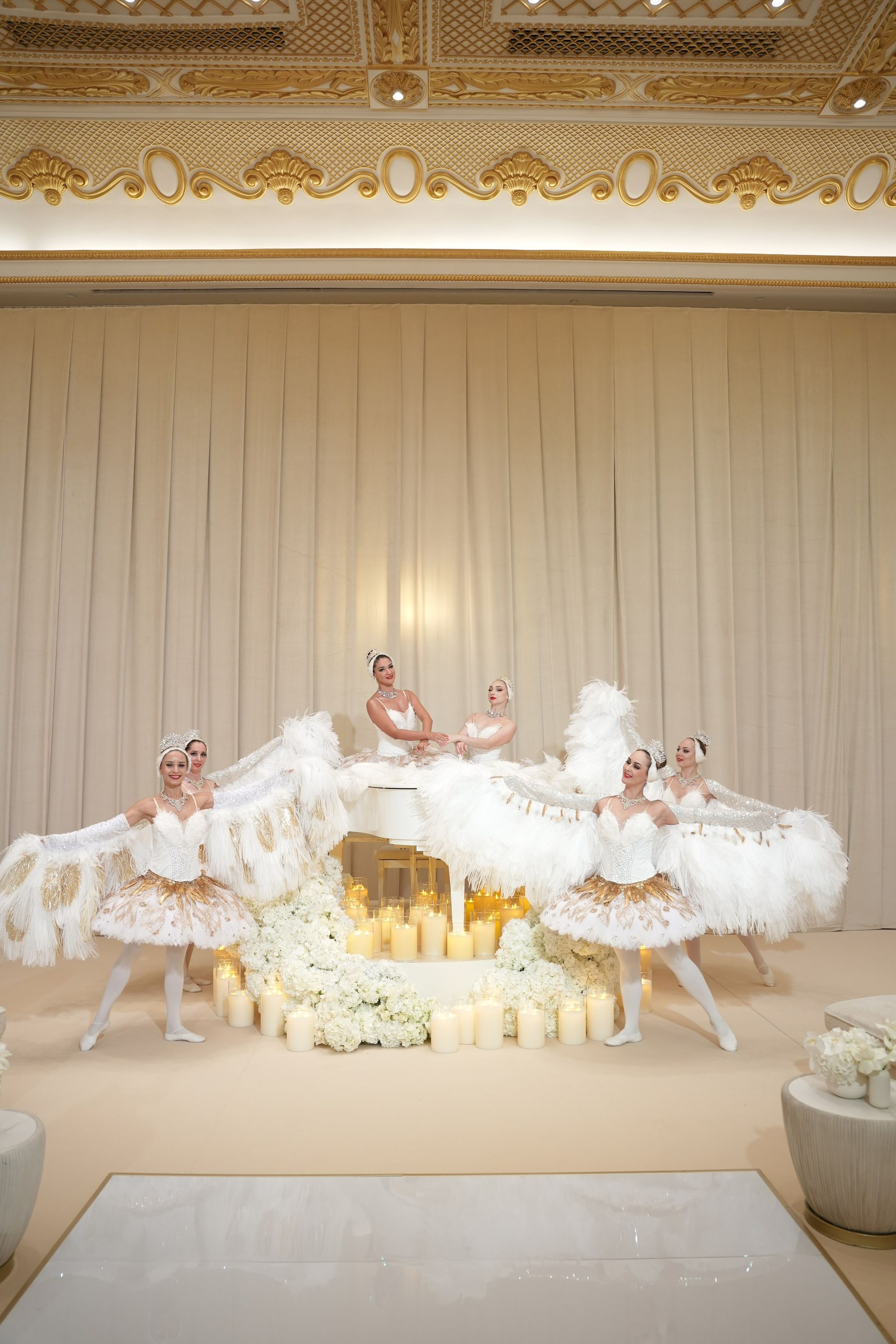 Ballerinas with feathered fans posed around a candlelit white grand piano at Raffles The Palm Dubai