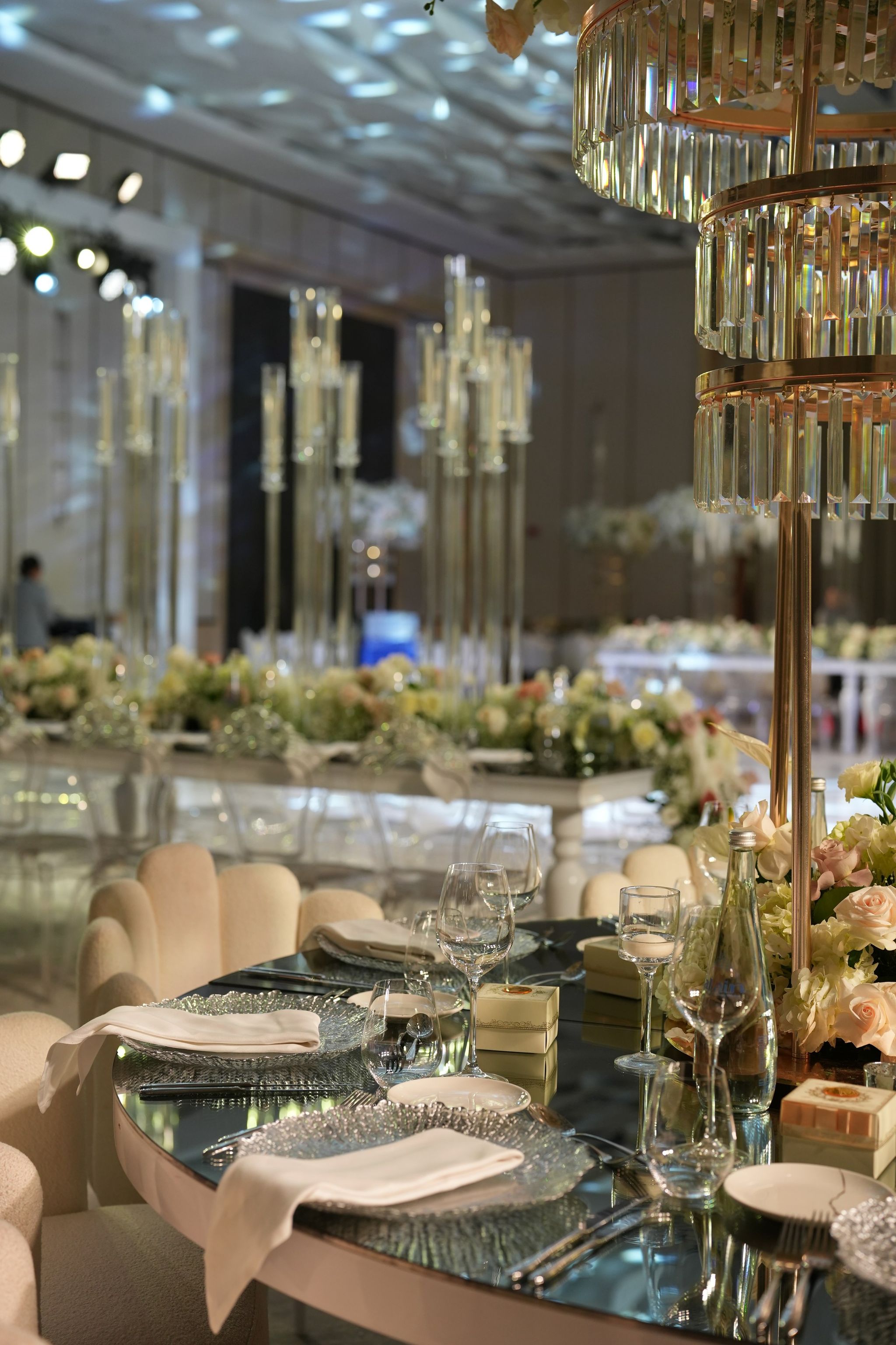 Place settings with charger plates and favour boxes under a gold and crystal centrepiece stand