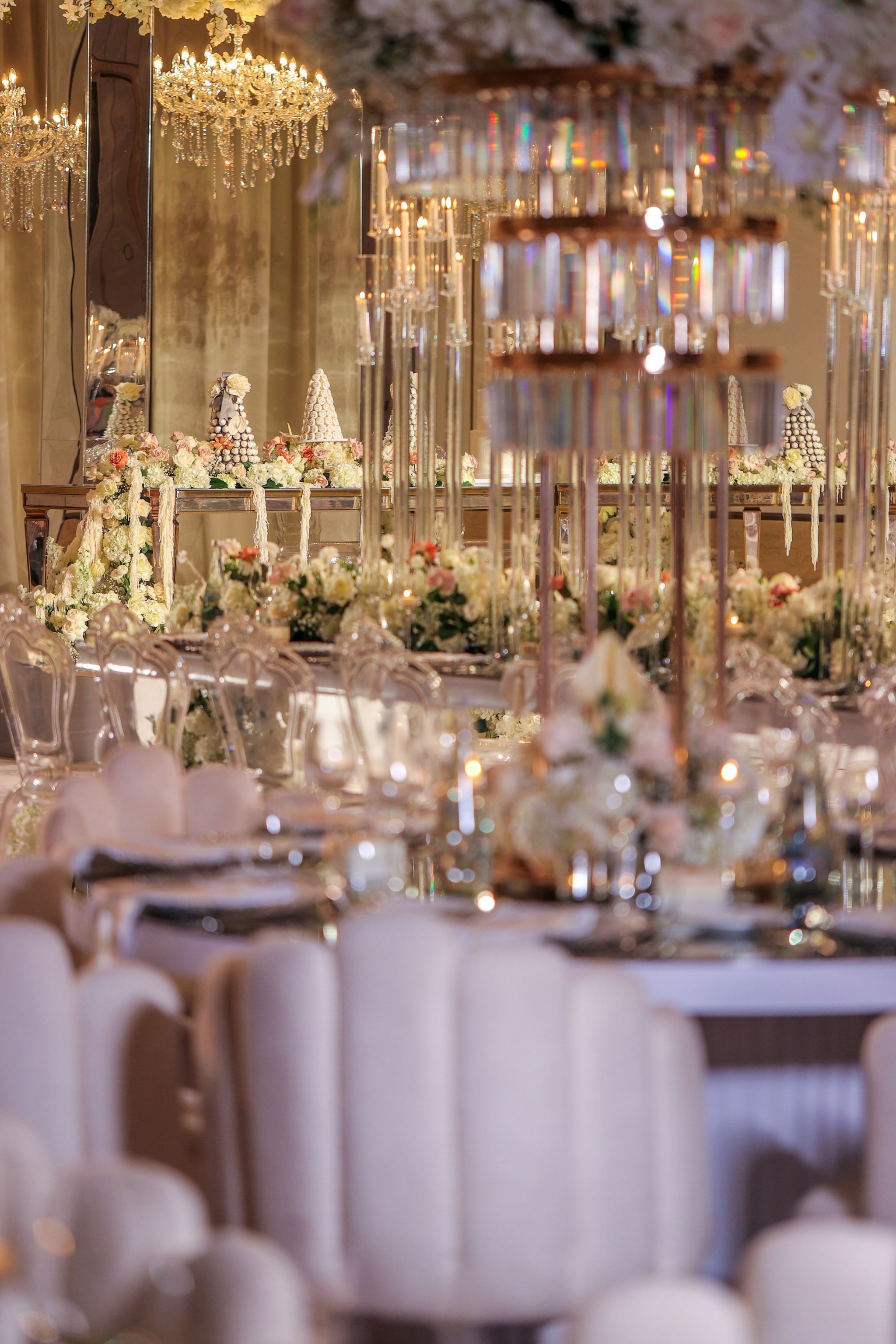 Shallow-focus view past crystal centrepieces and scalloped ivory chairs towards the floral stage