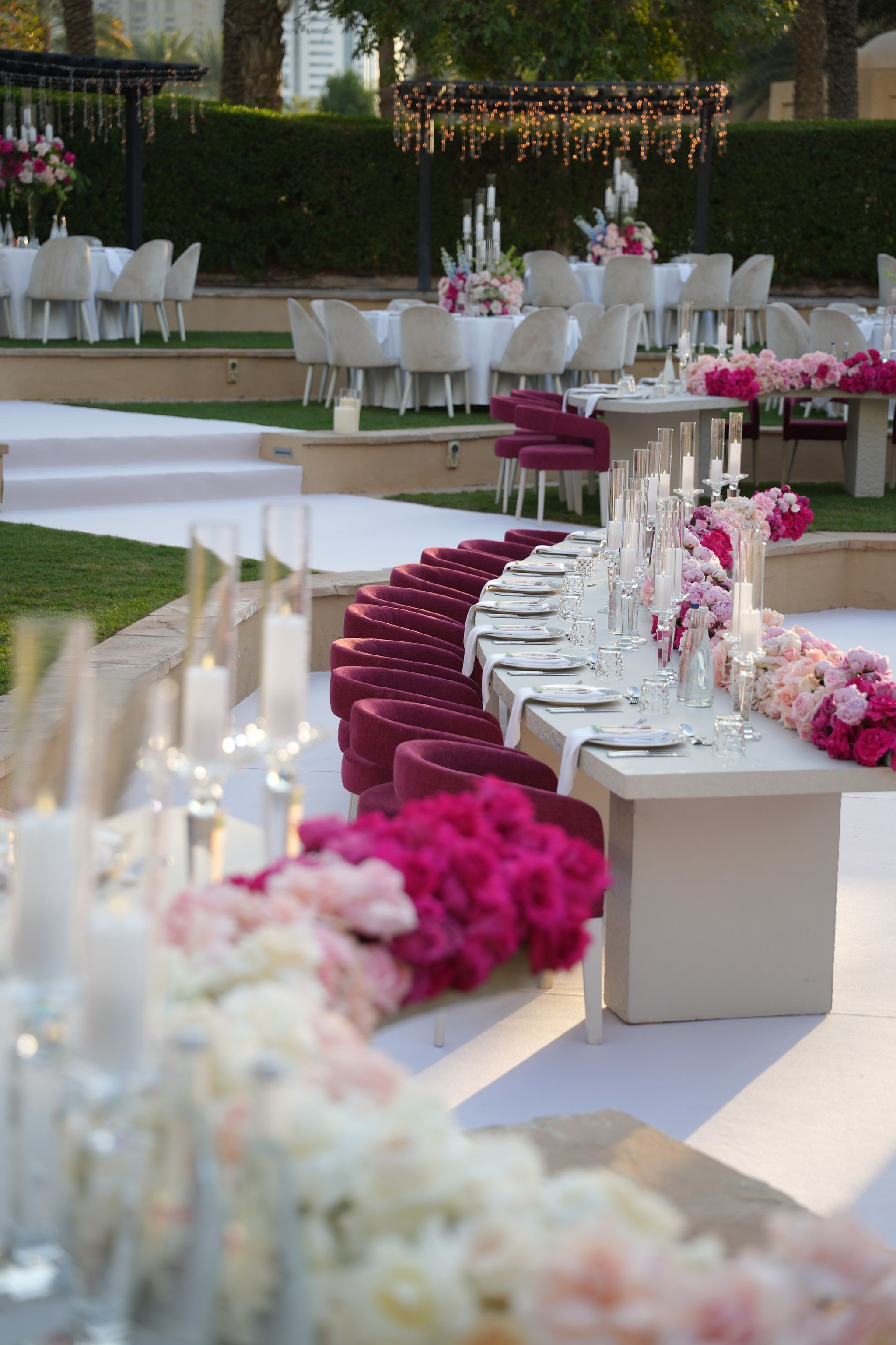 Curved banquet table set with magenta chairs, glass candles and ombré rose runner