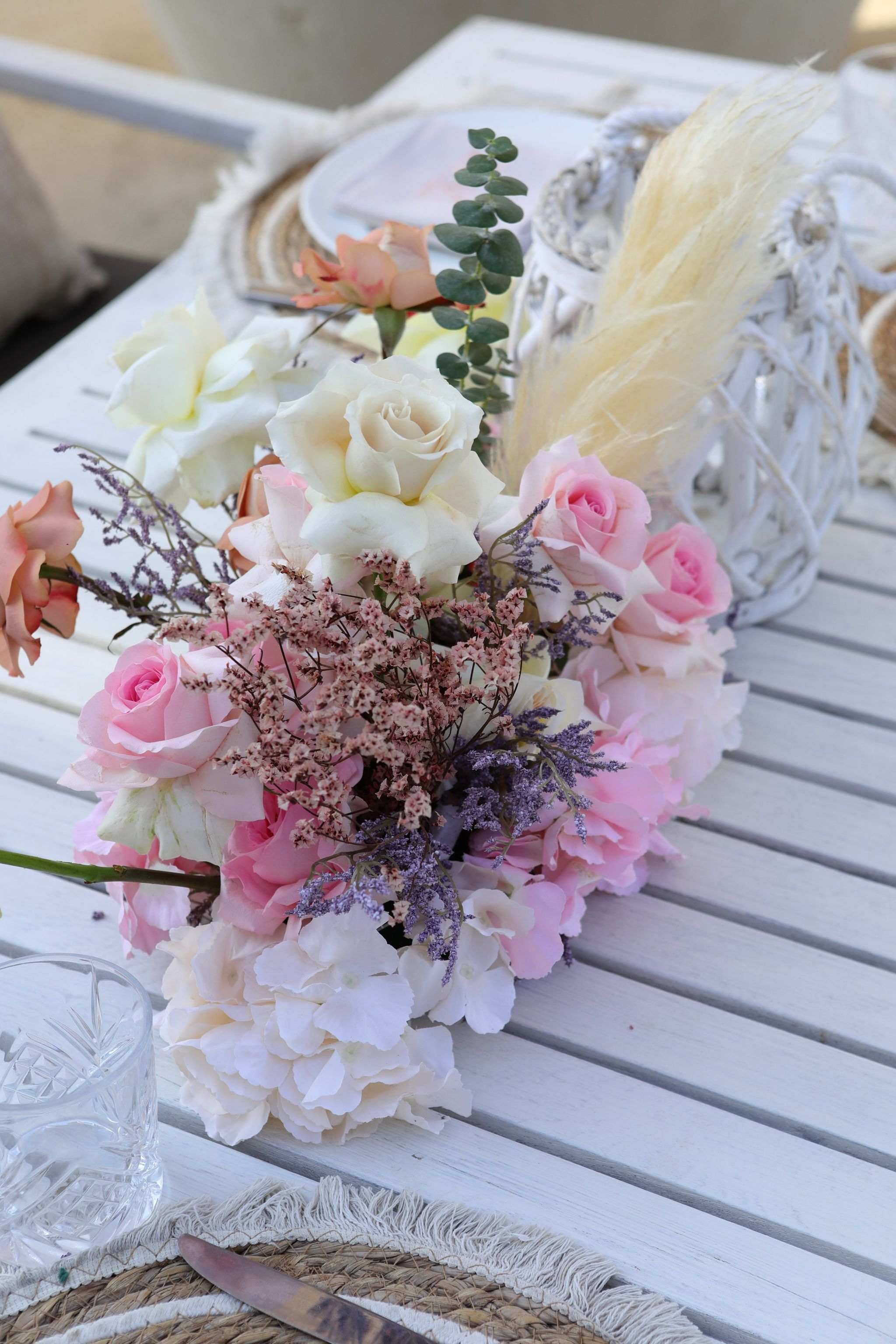 Runner of pink and ivory roses, hydrangea, limonium and pampas beside a white lantern