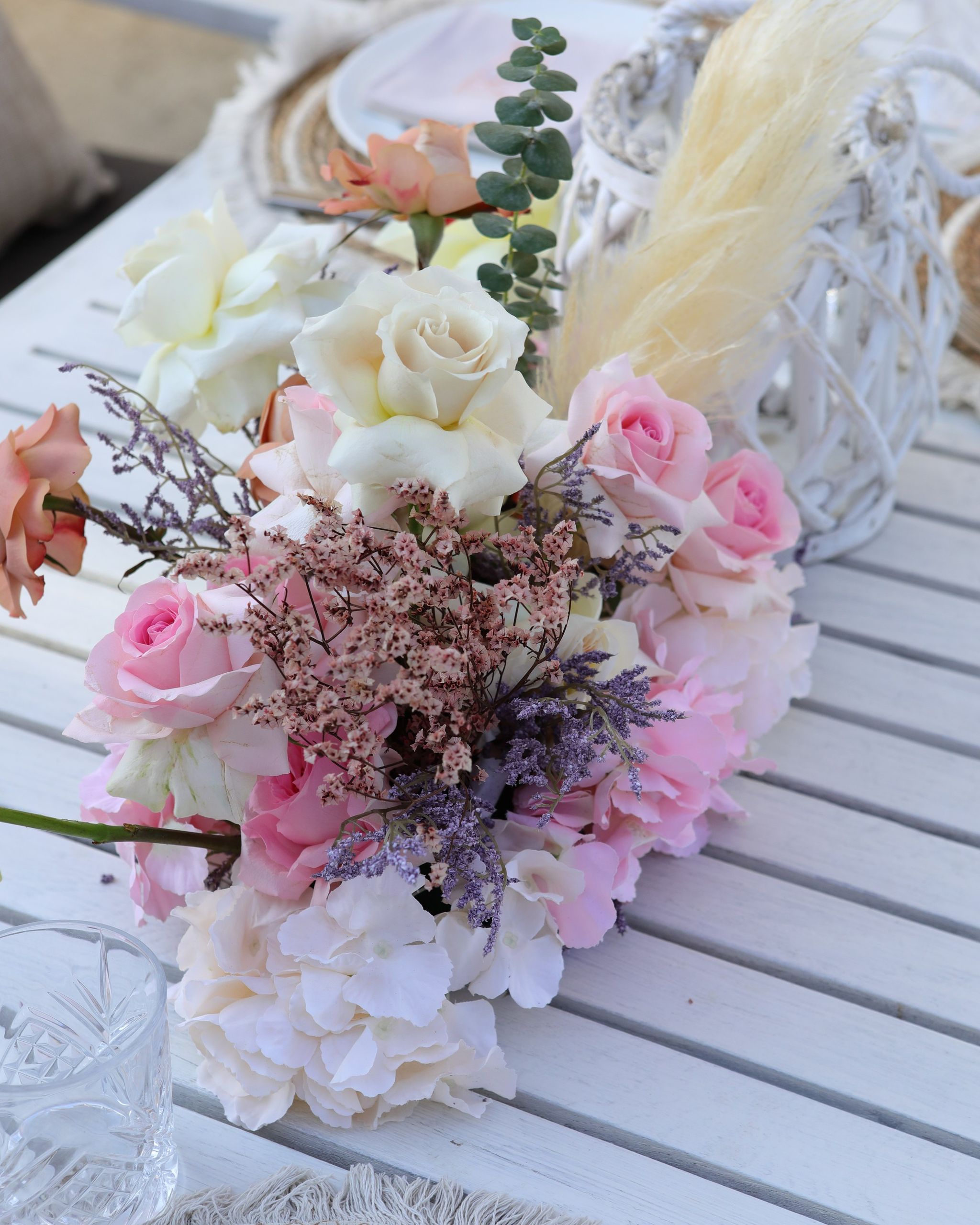 Runner of pink and ivory roses, hydrangea, limonium and pampas beside a white lantern