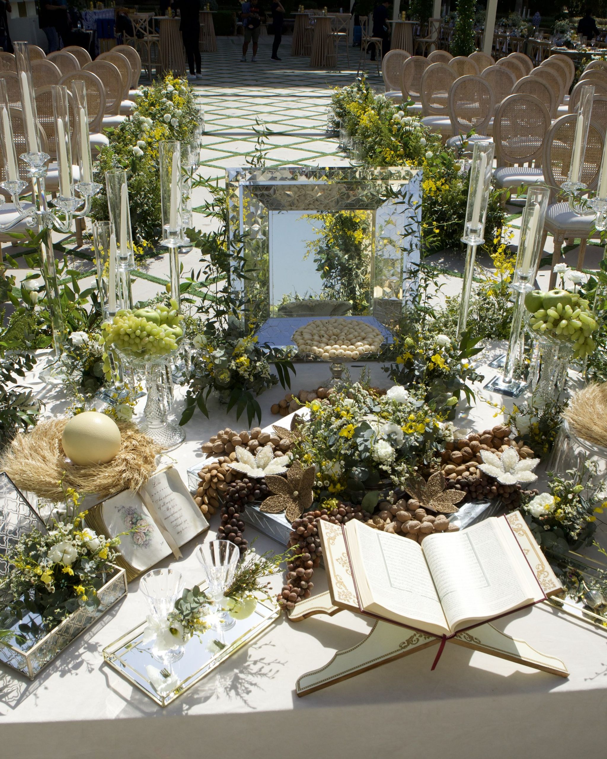 Sofreh aghd with a mirrored panel, open Quran, nests of eggs, nuts and lemons