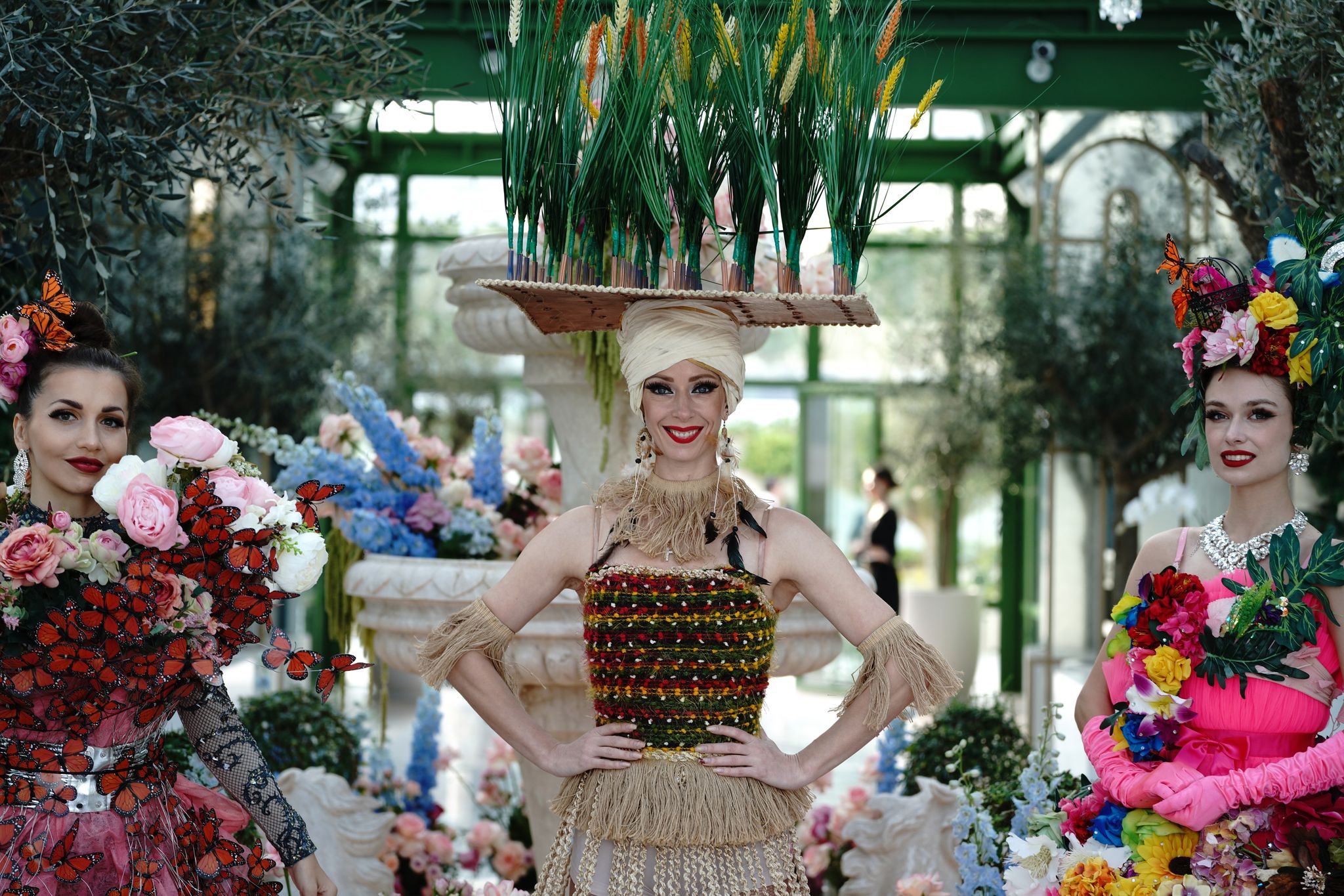 Three performers in floral and woven costumes posing before the conservatory fountain at Four Seasons Resort Dubai at Jumeirah Beach