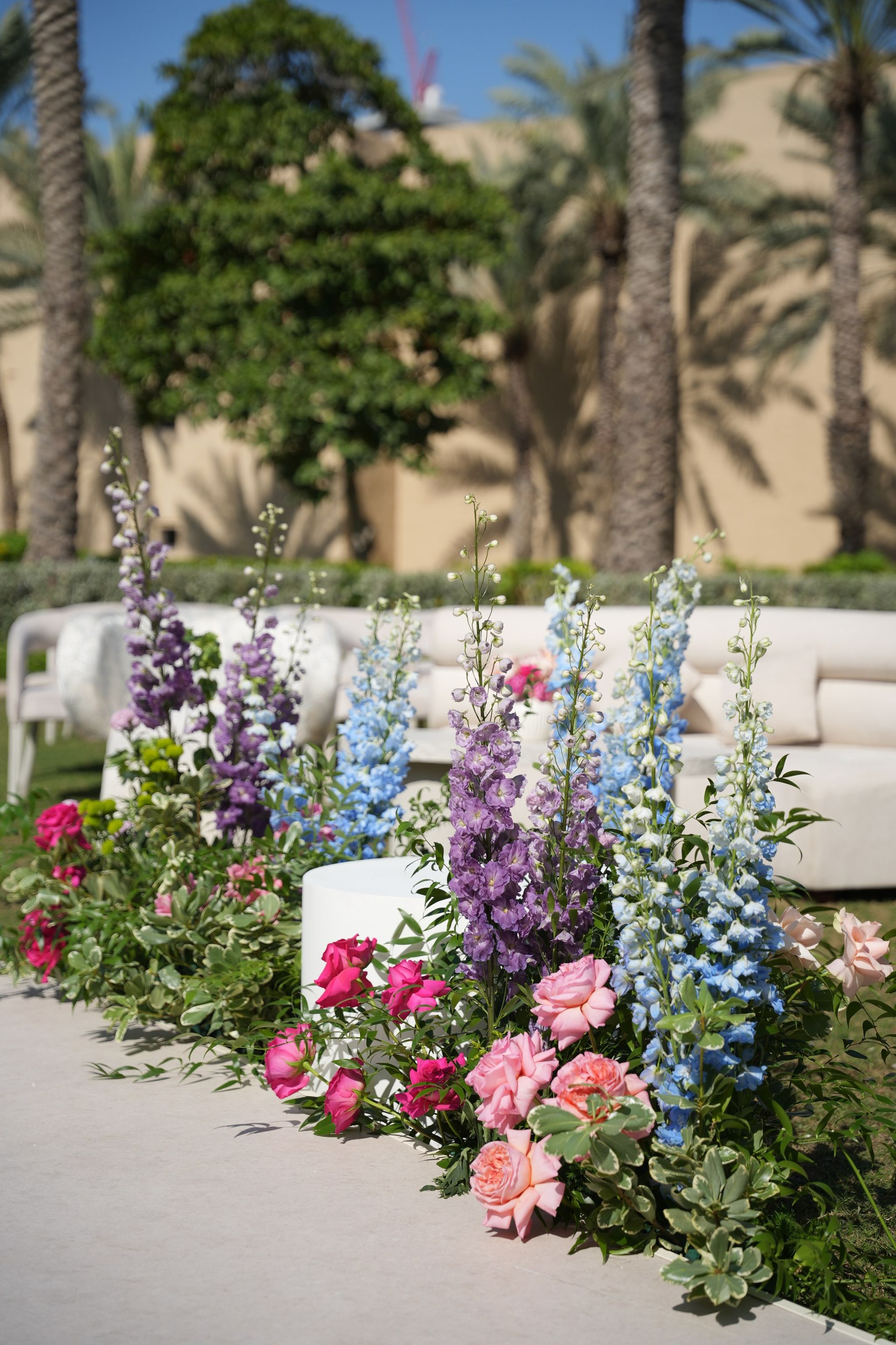 Blue and purple delphiniums with pink garden roses edging the white ceremony aisle