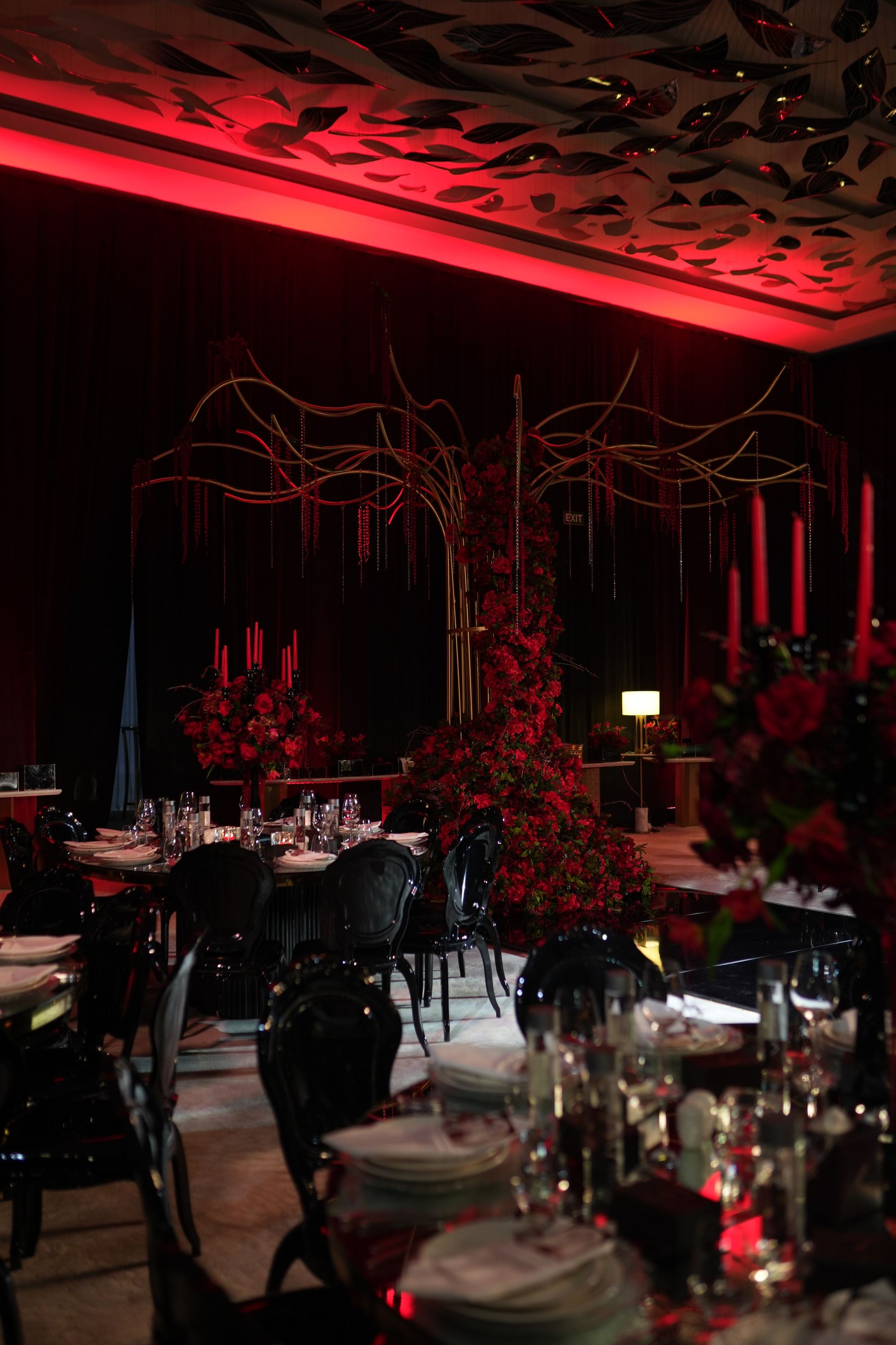 Gold branch sculpture rising from a column of red roses behind black-chaired tables at The St. Regis Dubai, The Palm