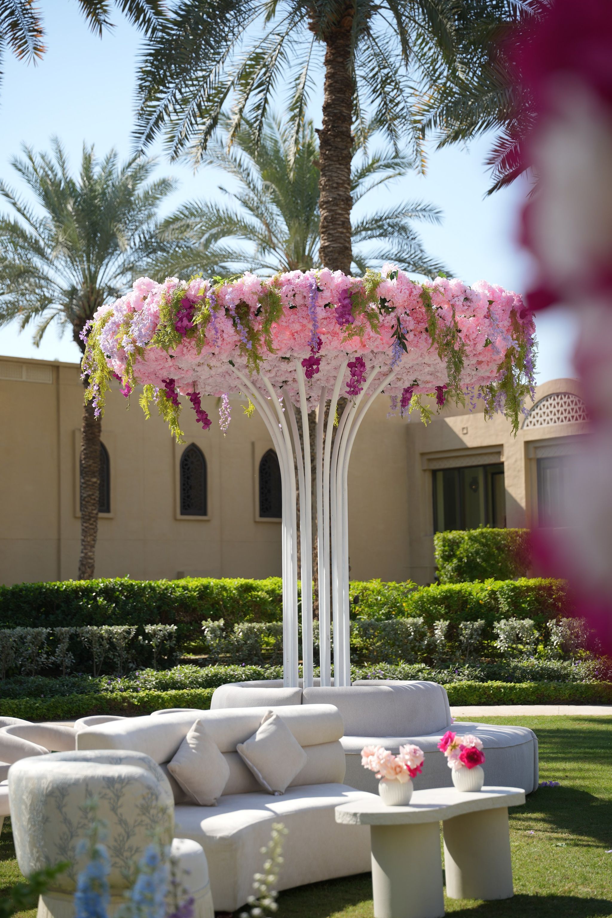 Pink hydrangea and wisteria canopy on slender white stems above an ivory garden lounge
