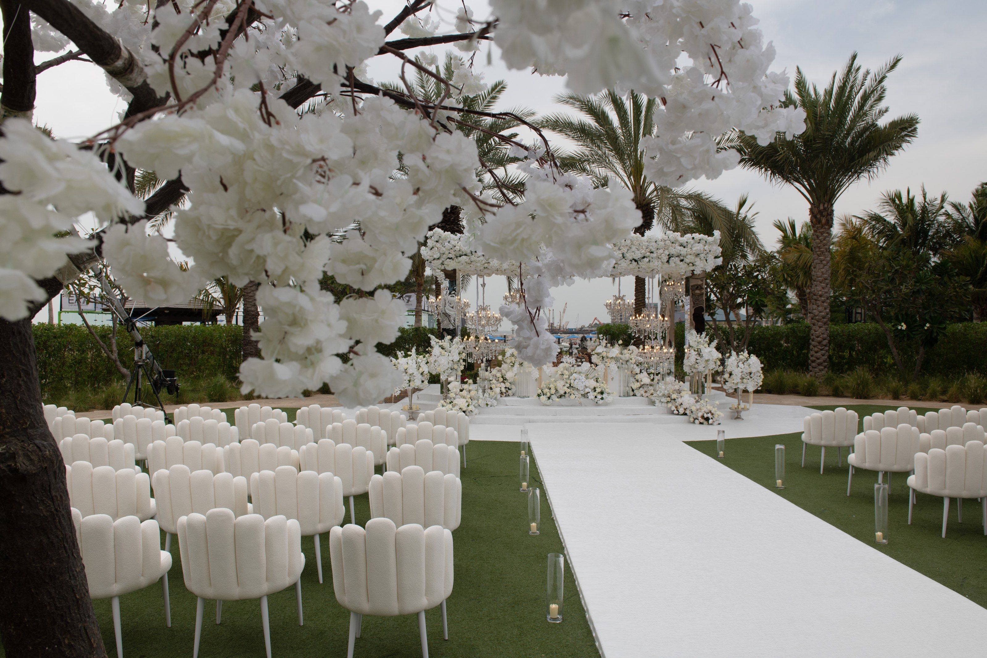 Blossom tree framing scalloped chairs and a white aisle at Four Seasons Resort Dubai at Jumeirah Beach