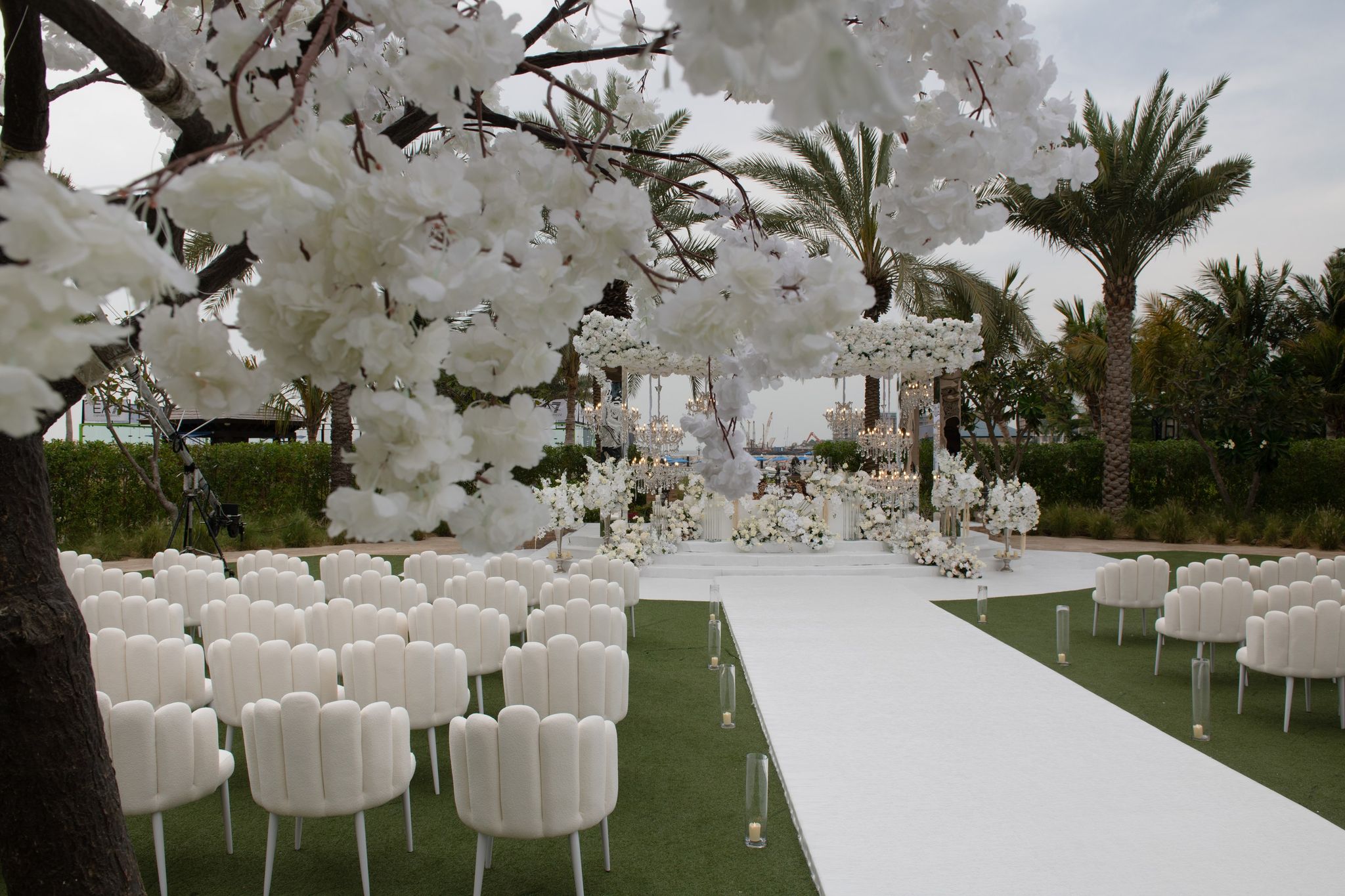 Blossom tree framing scalloped chairs and a white aisle at Four Seasons Resort Dubai at Jumeirah Beach