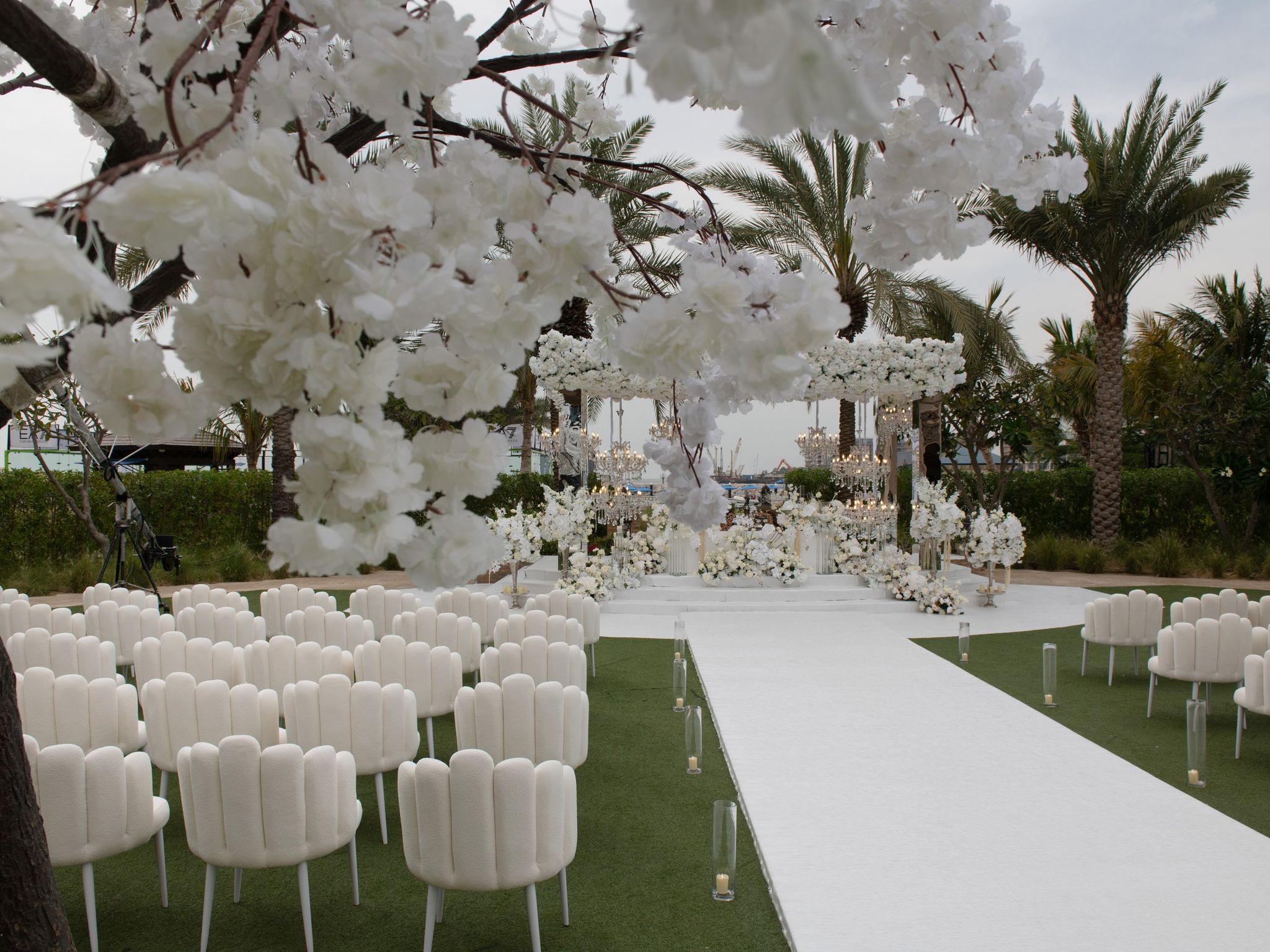 Blossom tree framing scalloped chairs and a white aisle at Four Seasons Resort Dubai at Jumeirah Beach