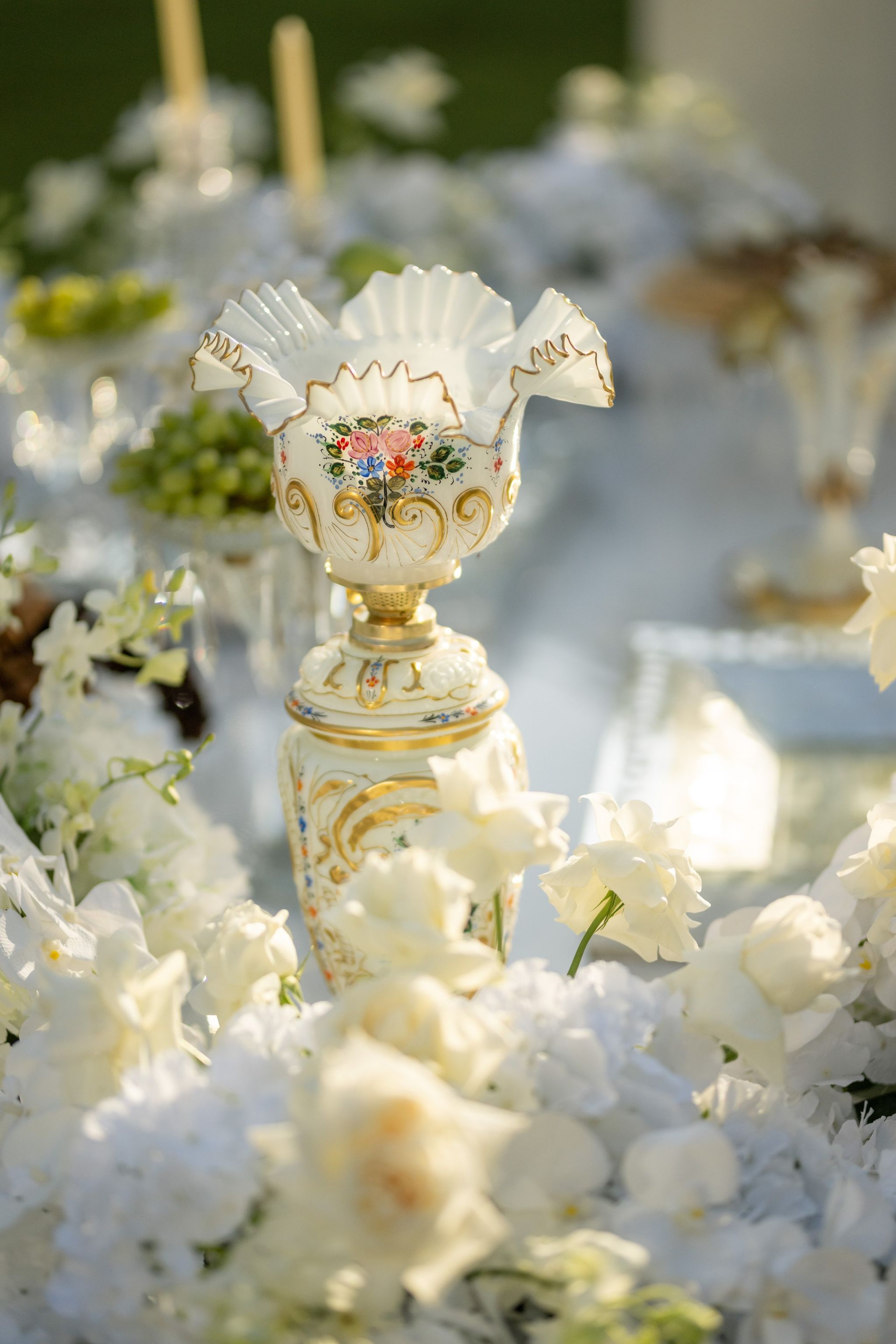 Hand-painted opaline vase with gilded rim rising from white roses and hydrangeas