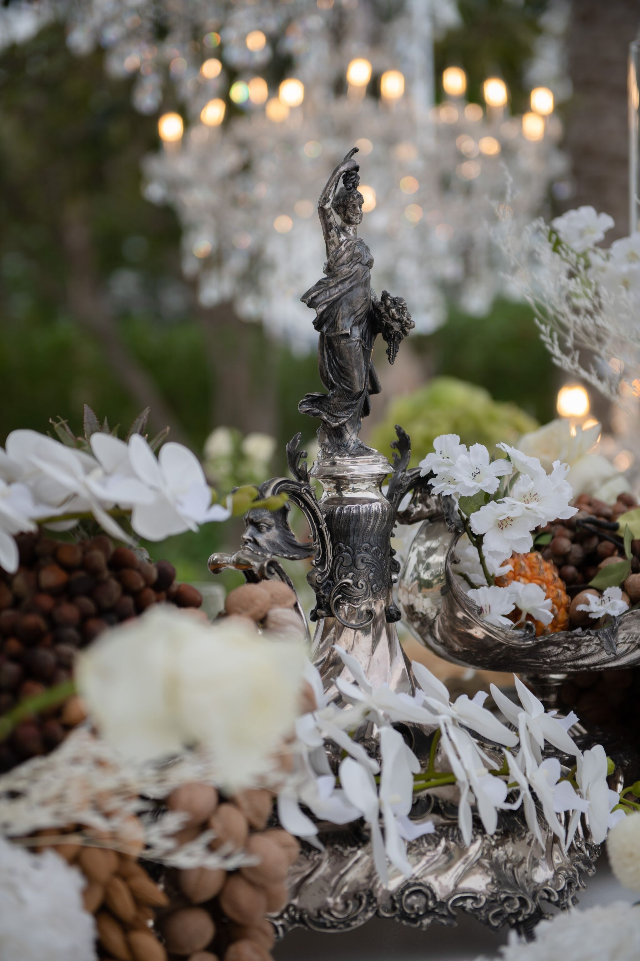 Silver figurine centrepiece with white orchids, a crystal chandelier glowing behind, at Four Seasons Resort Dubai at Jumeirah Beach