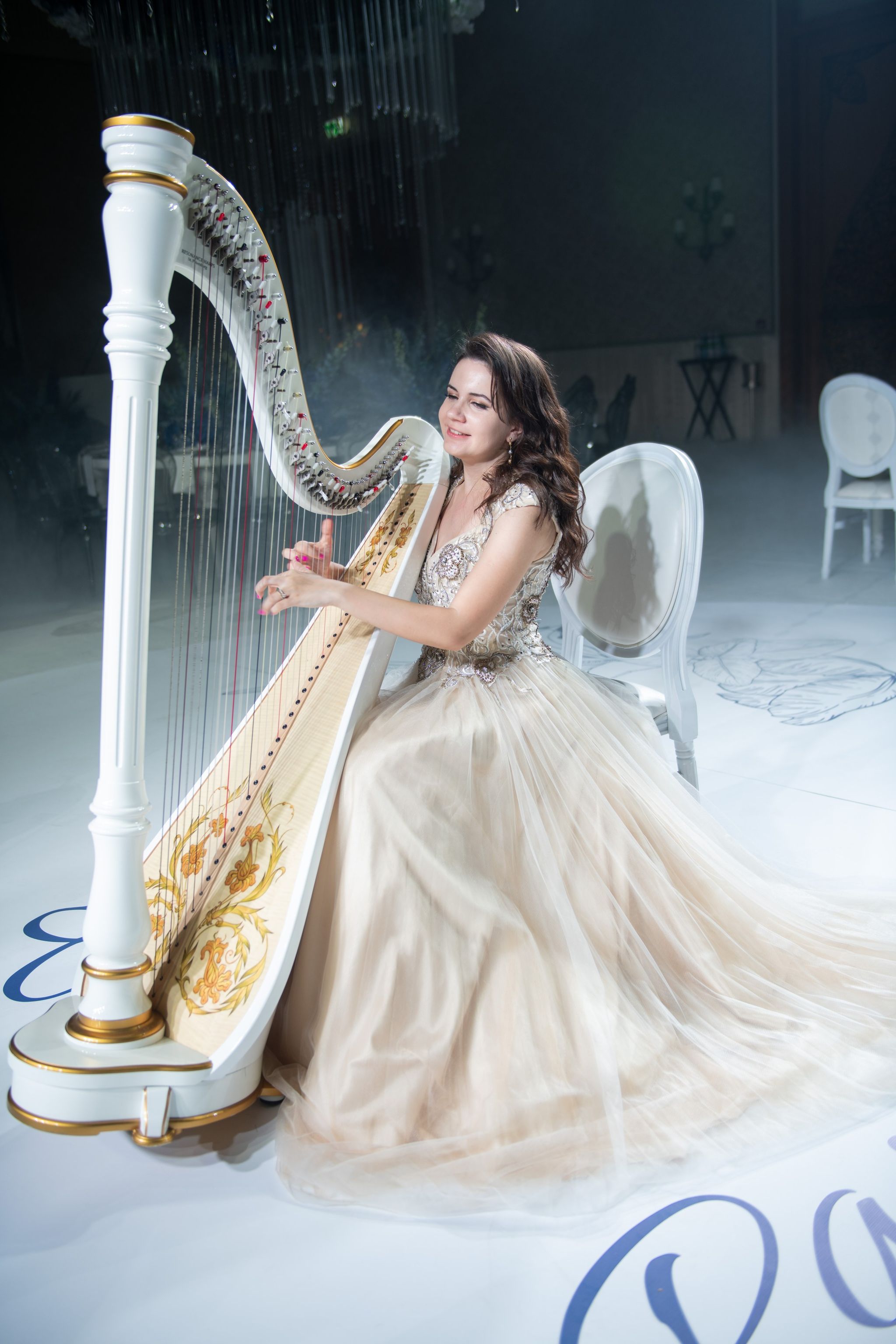 A harpist in a tulle gown playing a white and gold harp at Four Seasons Resort Dubai at Jumeirah Beach