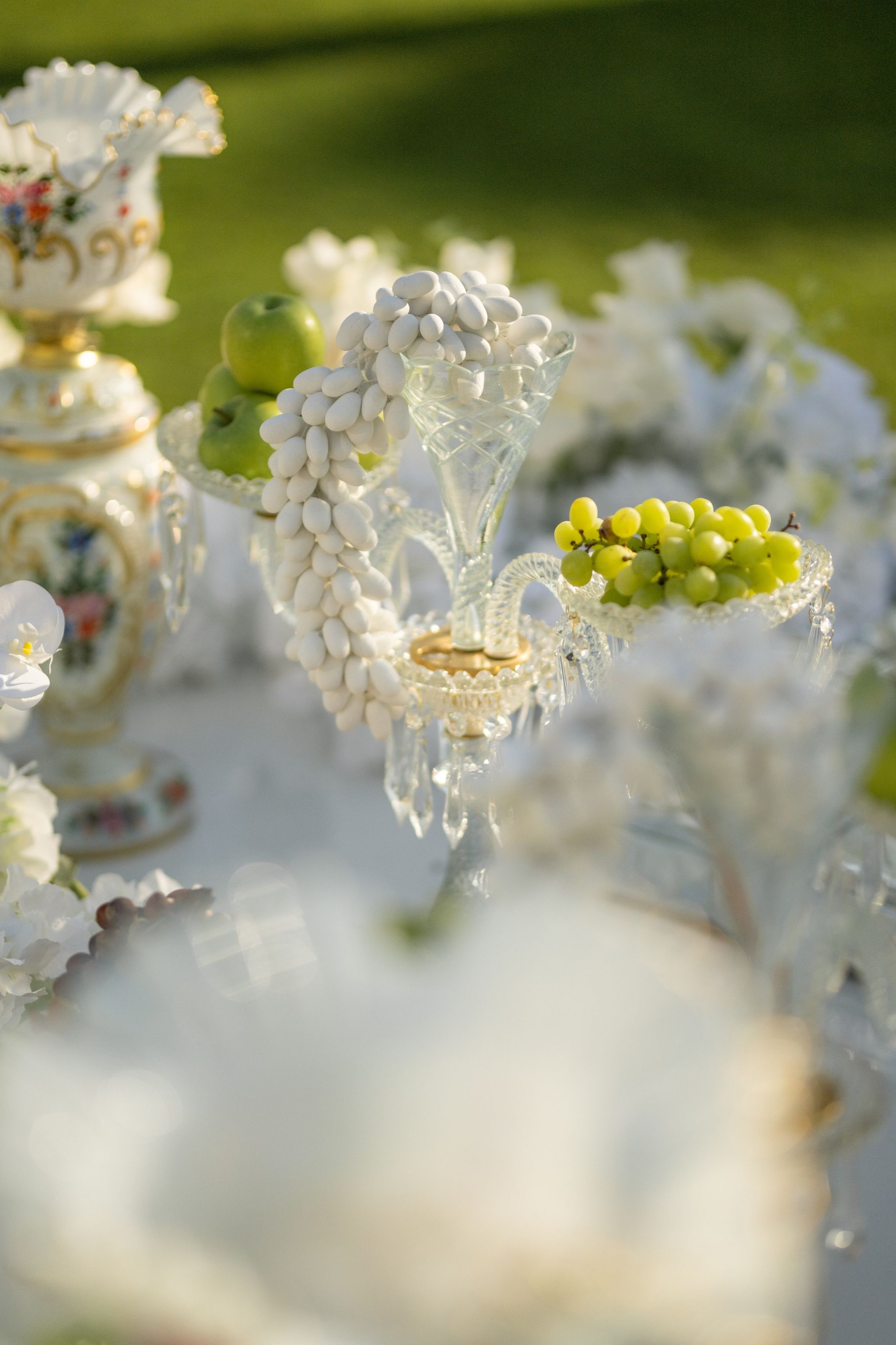 Crystal stand piled with sugared almonds beside green grapes and a hand-painted opaline vase