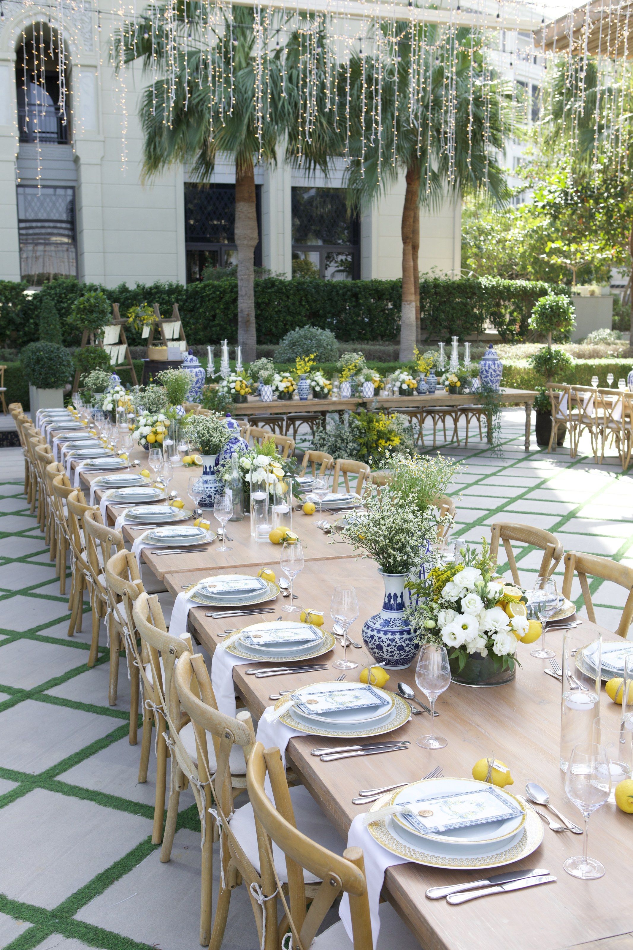 Courtyard view of crossback chairs along lemon-dressed tables under hanging string lights